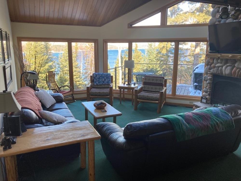 Image 1: Carpeted living area with wooden ceiling, vaulted ceiling, and a stone fireplace, Living Room