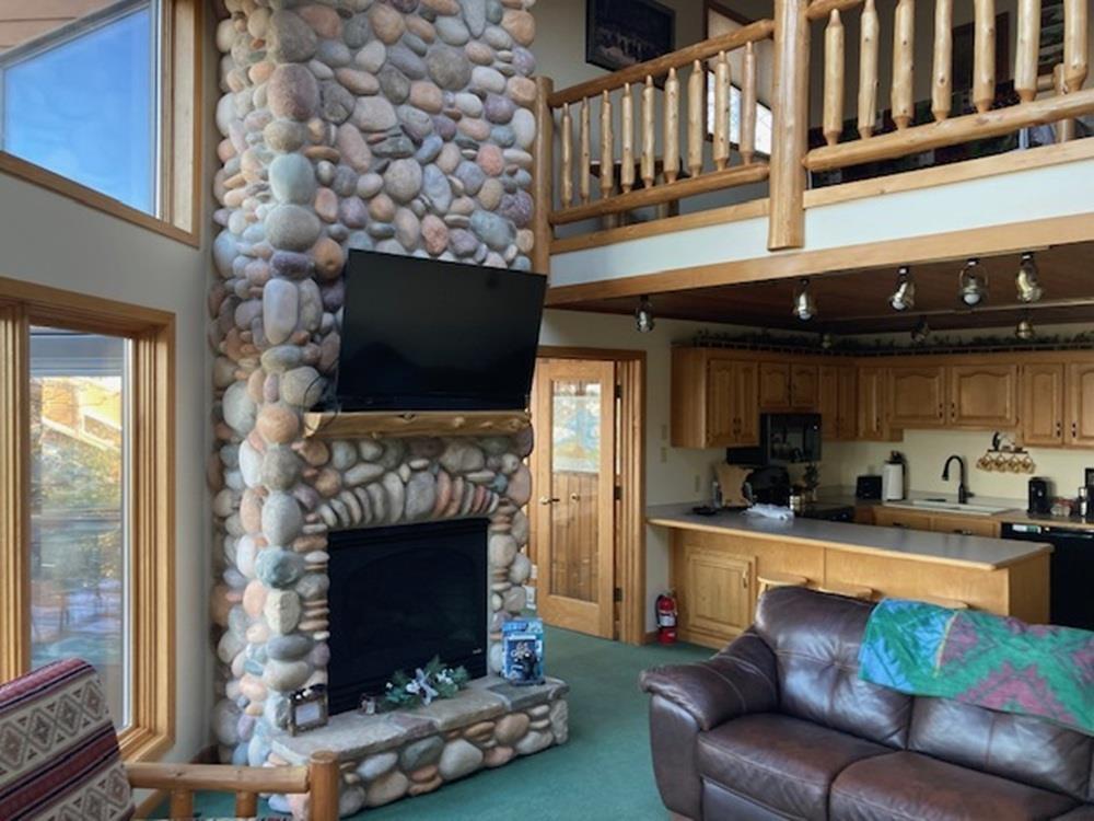Image 3: Living area with carpet flooring, a stone fireplace, and a towering ceiling, Living Room