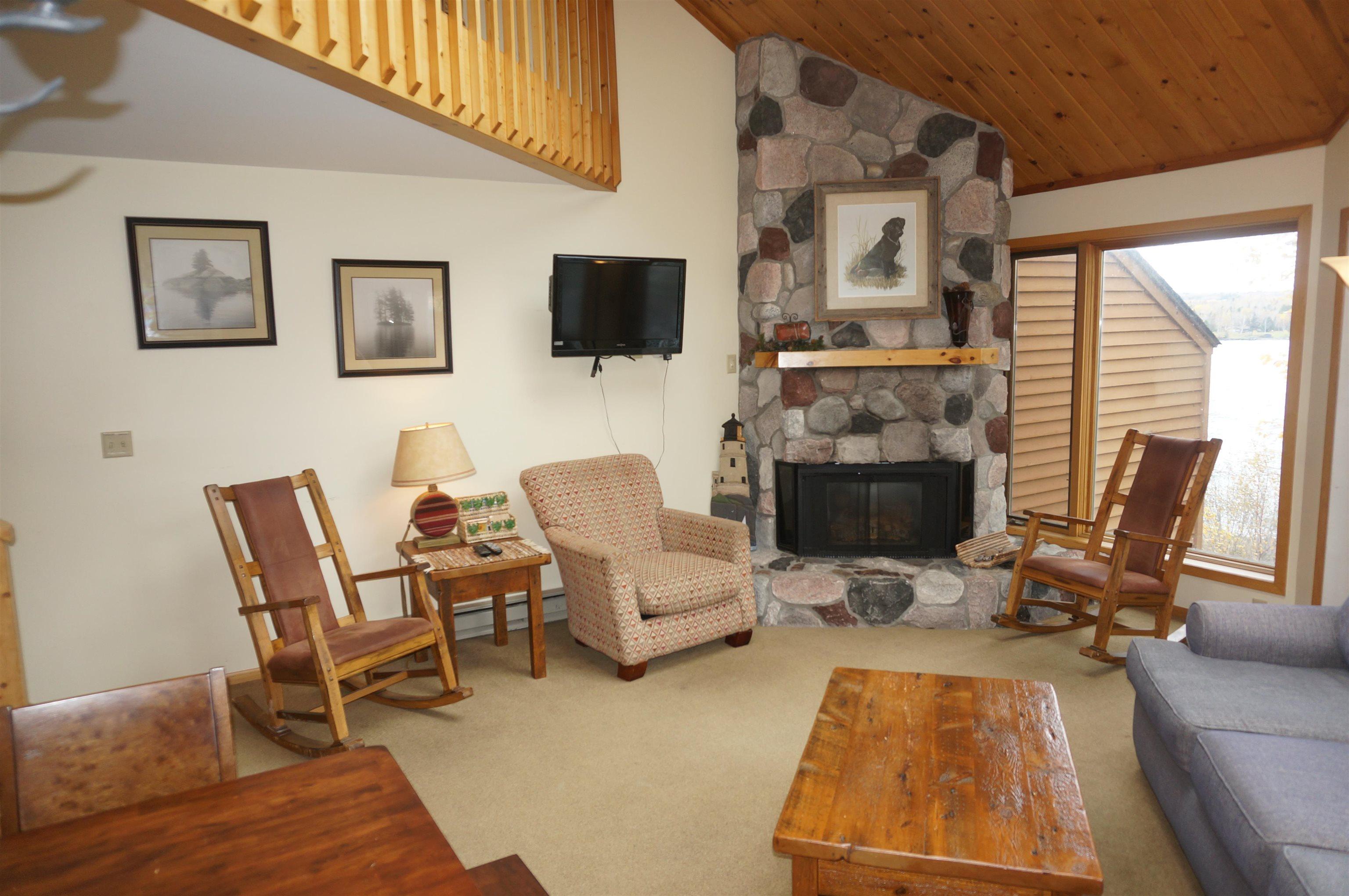 Image 2: Carpeted living room featuring high vaulted ceiling, a stone fireplace, a baseboard heating unit, and wood ceiling, Living Room