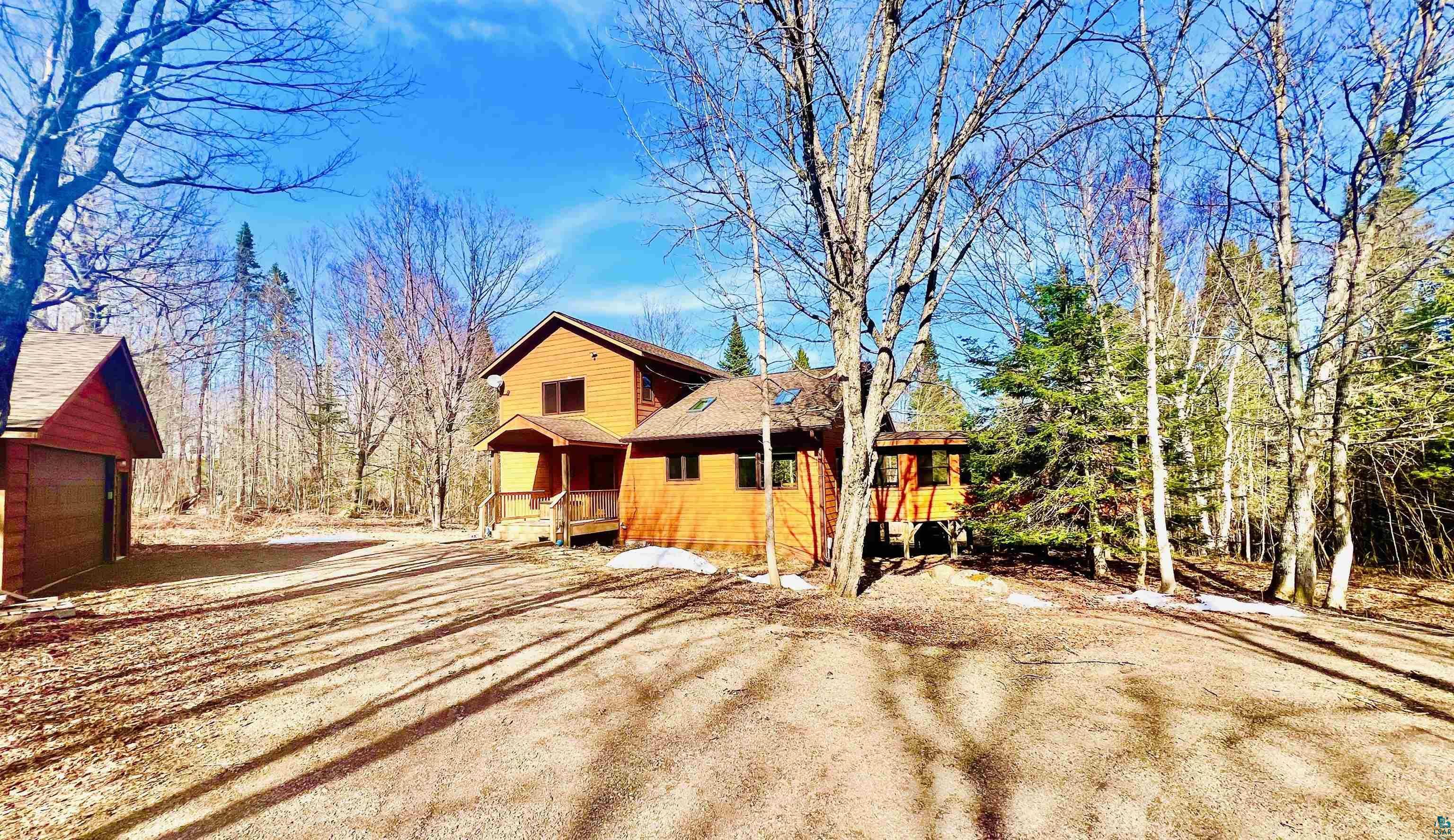 Image 2: Wood-sided home with a covered front porch and a separate detached garage structure, Home and Garage