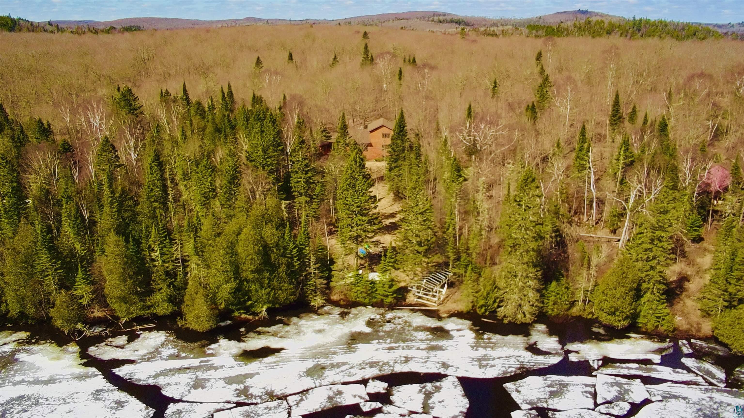 Image 3: Wooded shoreline property featuring a cabin-style residence and a slatted boat shelter, Ice on Caribou Lake