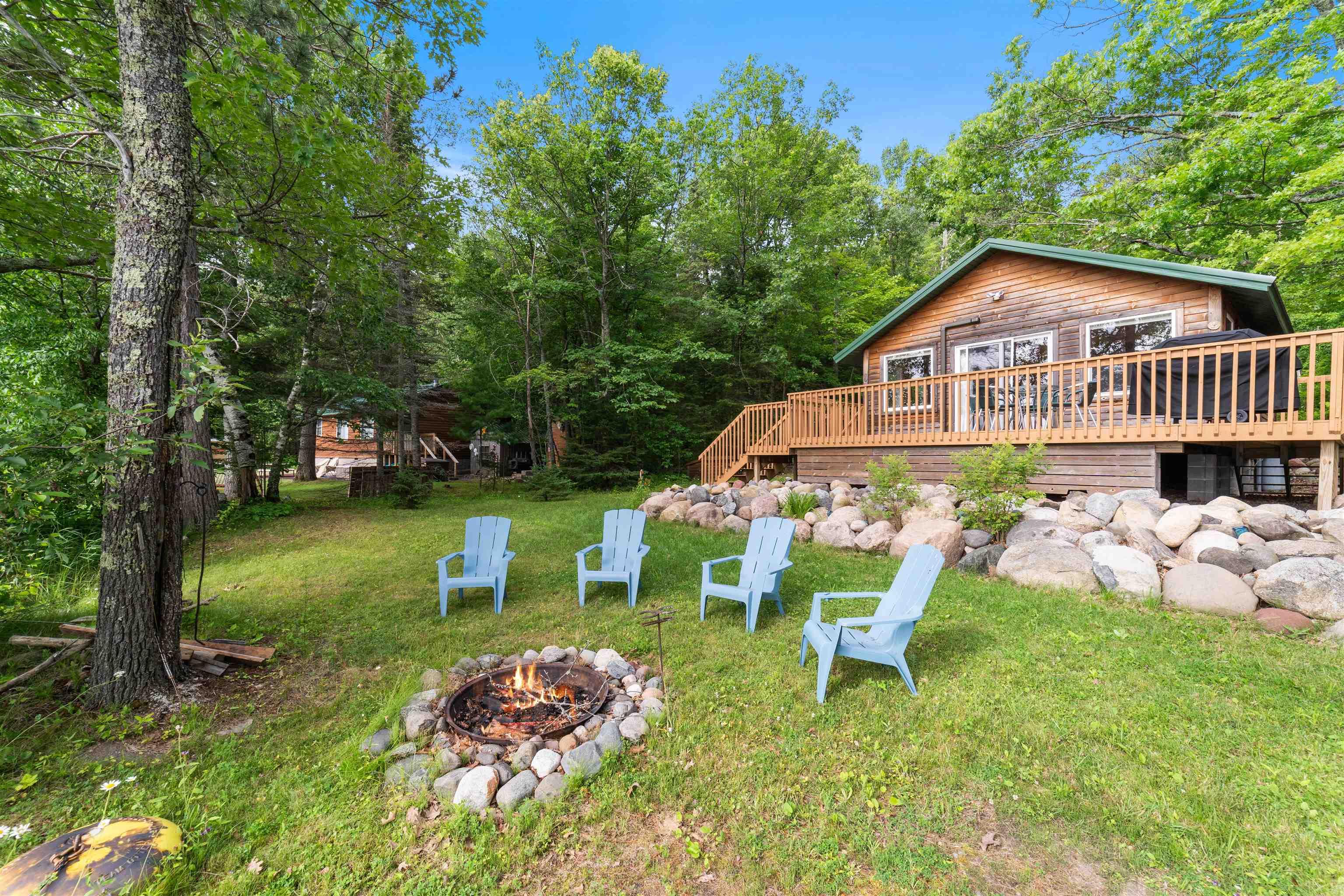 Image 1: View of grassy yard featuring a fire pit and a wooden deck, Yard