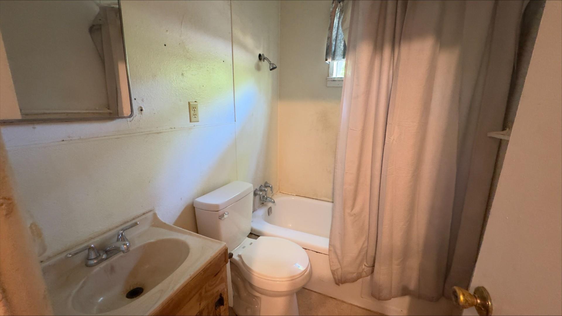 Image 1: Bathroom featuring a wood-finish vanity with an integrated sink, a white toilet, and a white bathtub with a shower fixture, Bathroom