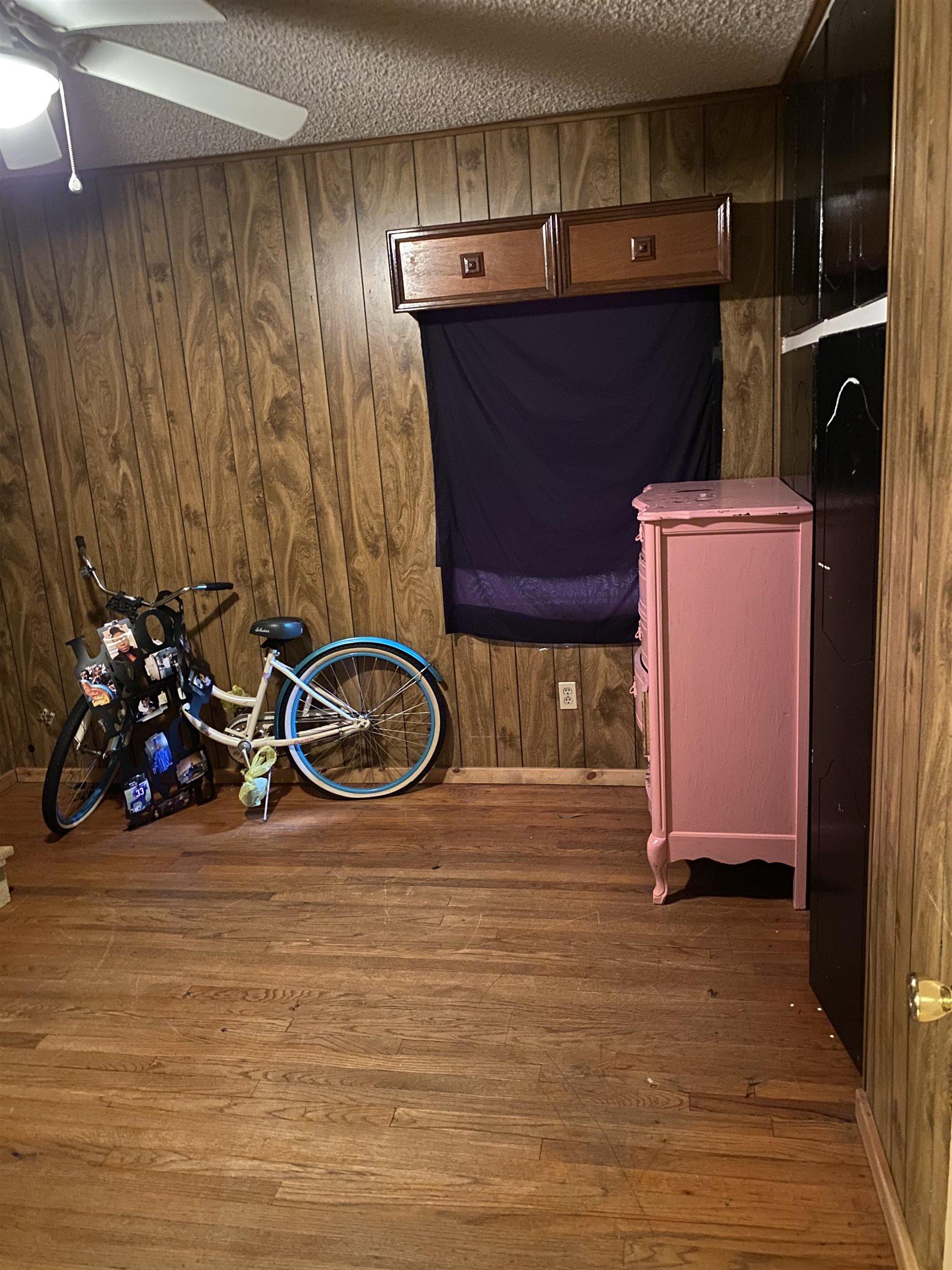 Image 2: Wood-finish flooring with wood paneling walls, Bedroom
