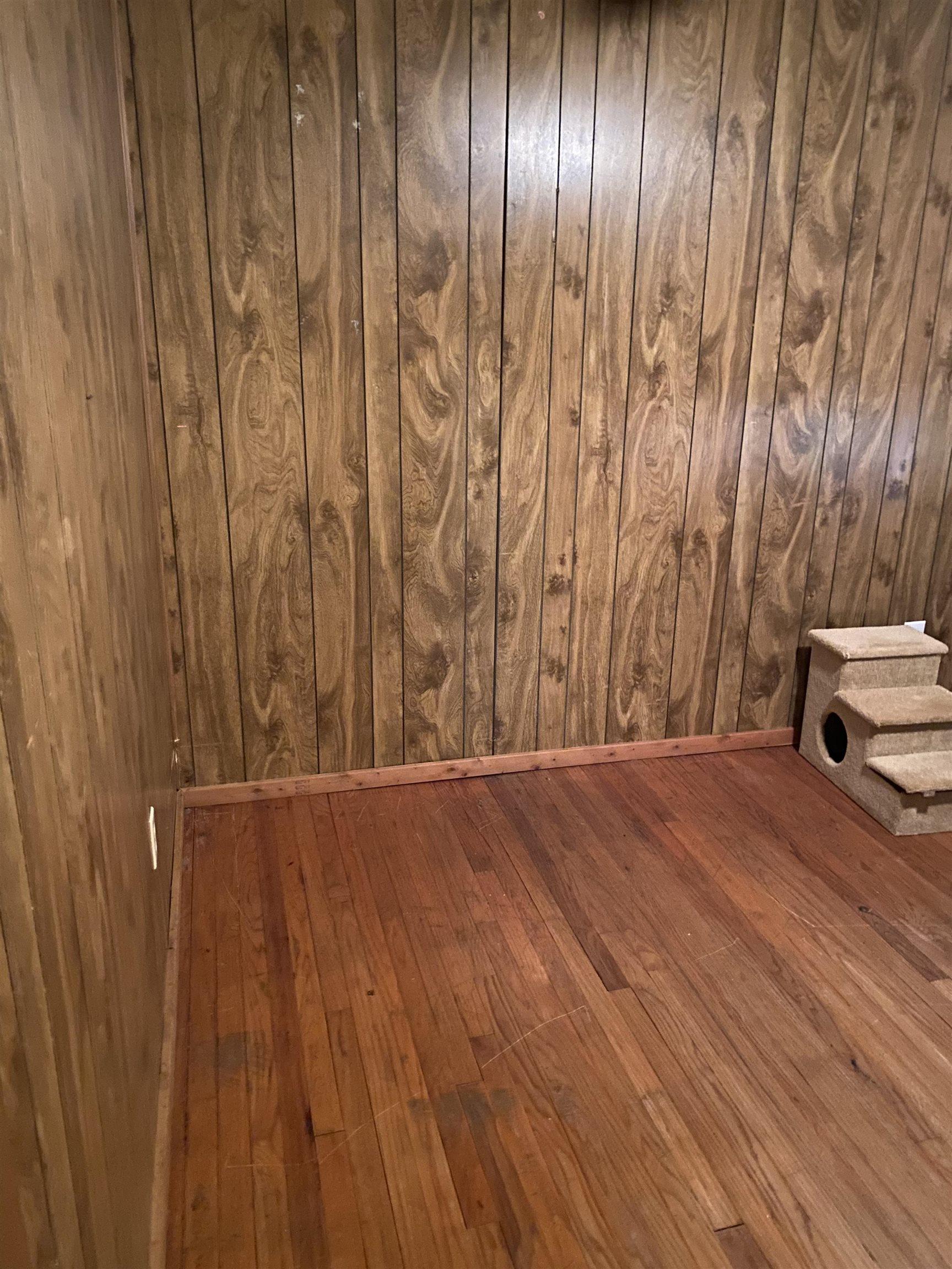 Image 3: Wood-finish paneled walls and wood-finish flooring define this space, Bedroom
