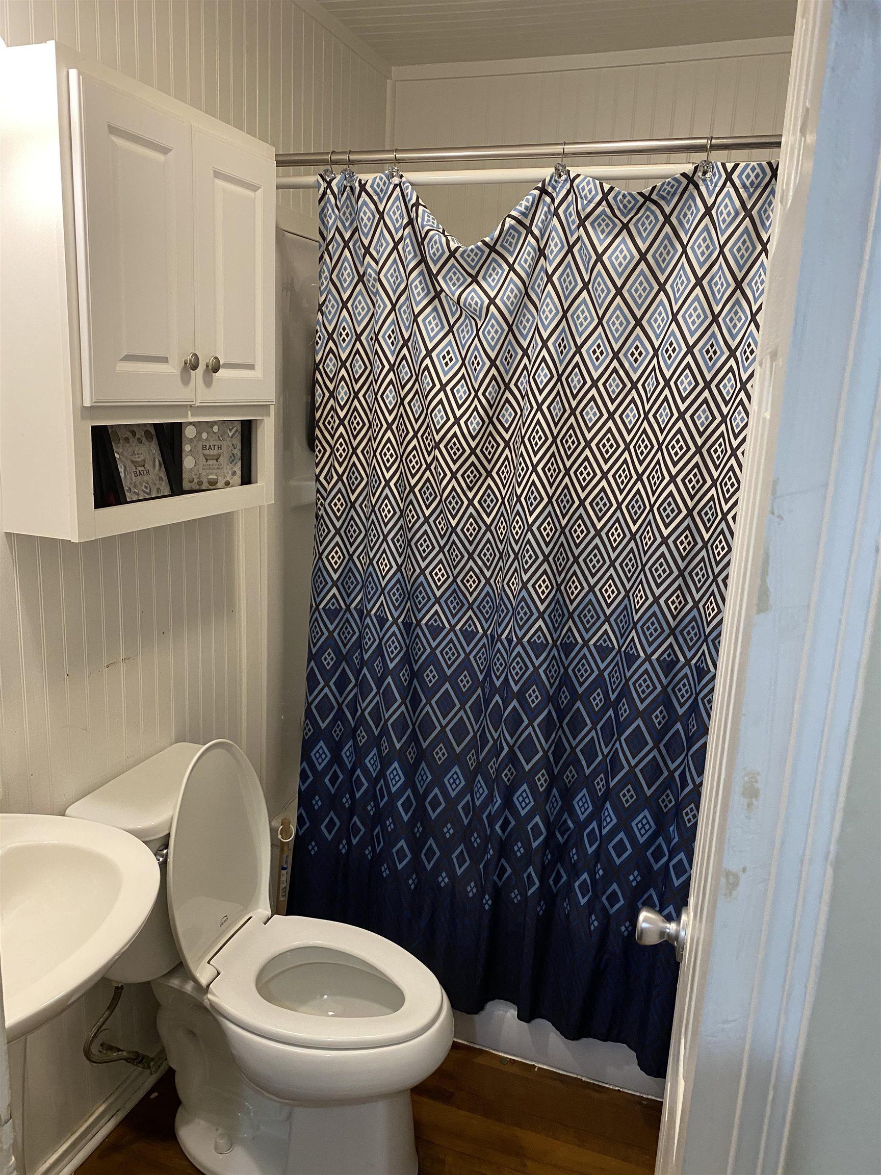 Image 3: Compact bathroom featuring beadboard wall paneling and wood-finish flooring, Bathroom