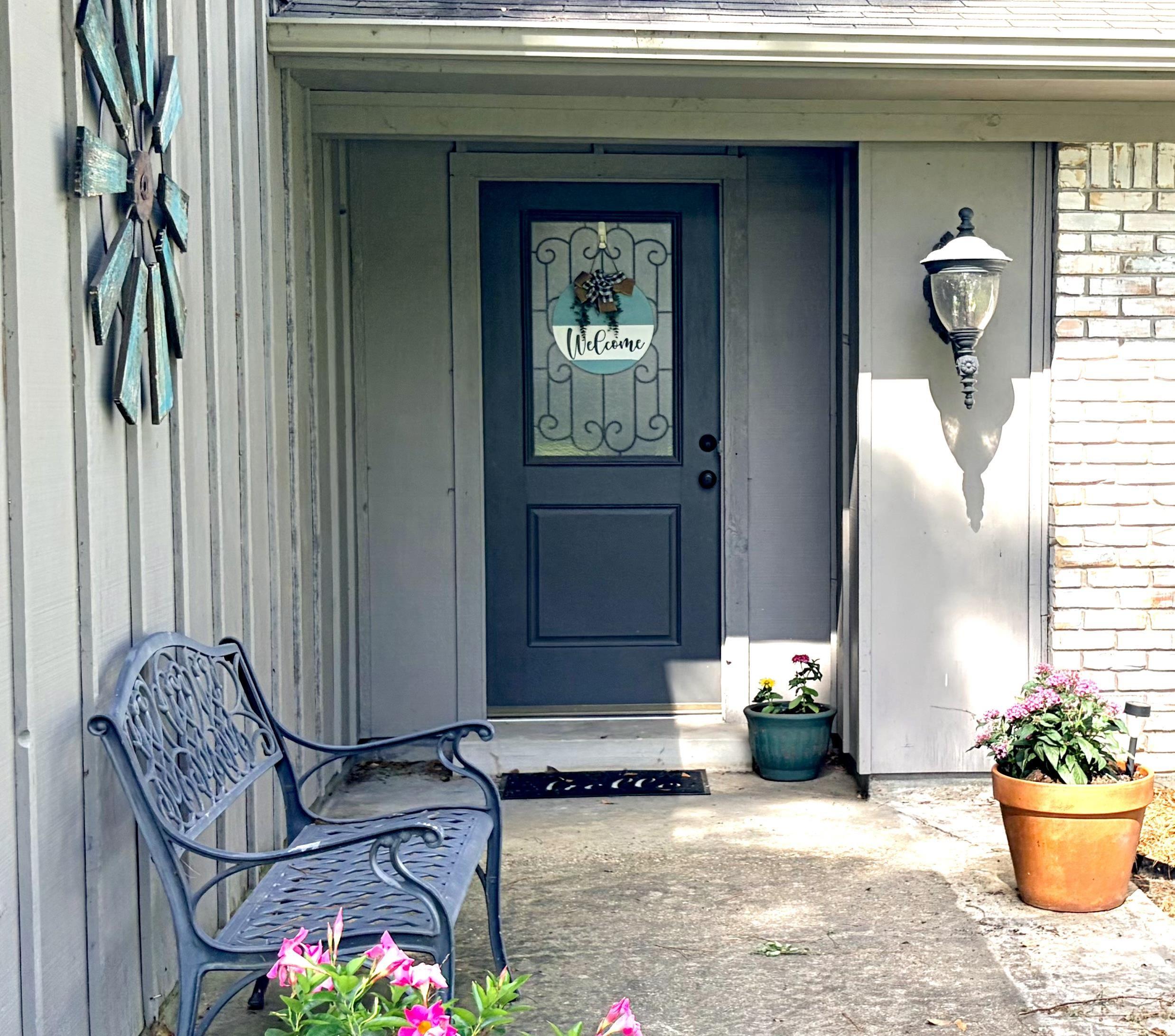 Image 2: Front entrance featuring a dark paneled door with decorative glass, an exterior wall lantern, and light brick siding, Entry