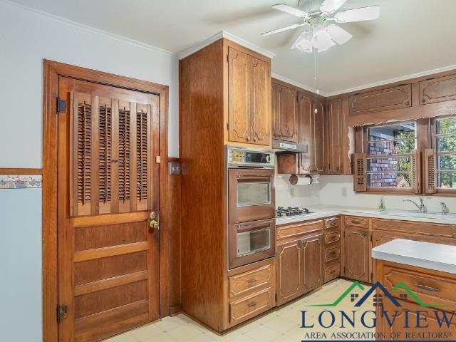 Image 2: Kitchen featuring light flooring, stainless steel double oven, light countertops, ornamental molding, and brown cabinets, Kitchen