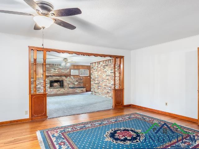 Image 3: Unfurnished living room with wood finished floors, a fireplace, and brick wall, Living Room