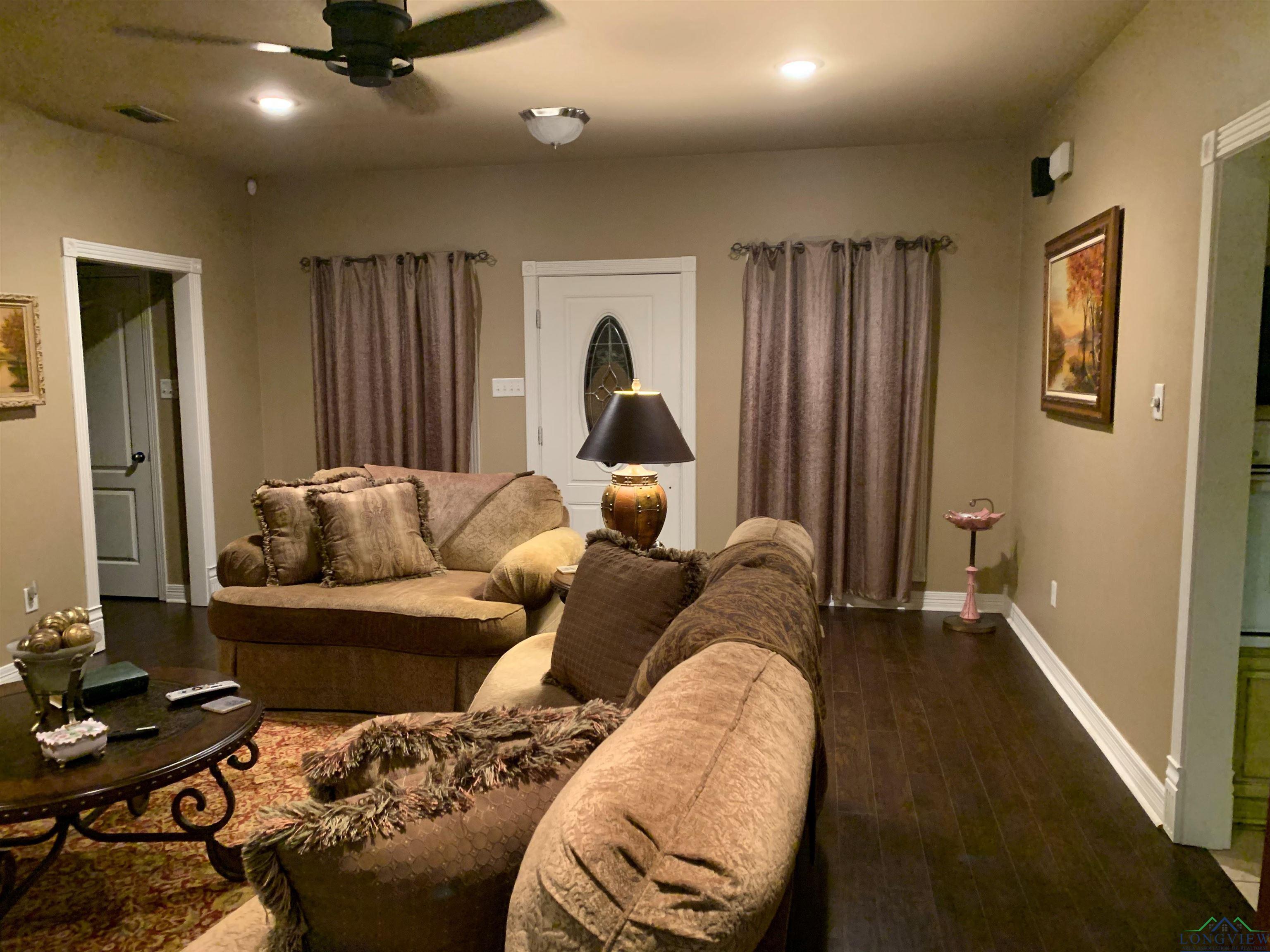 Image 1: Living room featuring dark wood-type flooring and ceiling fan, Living Room