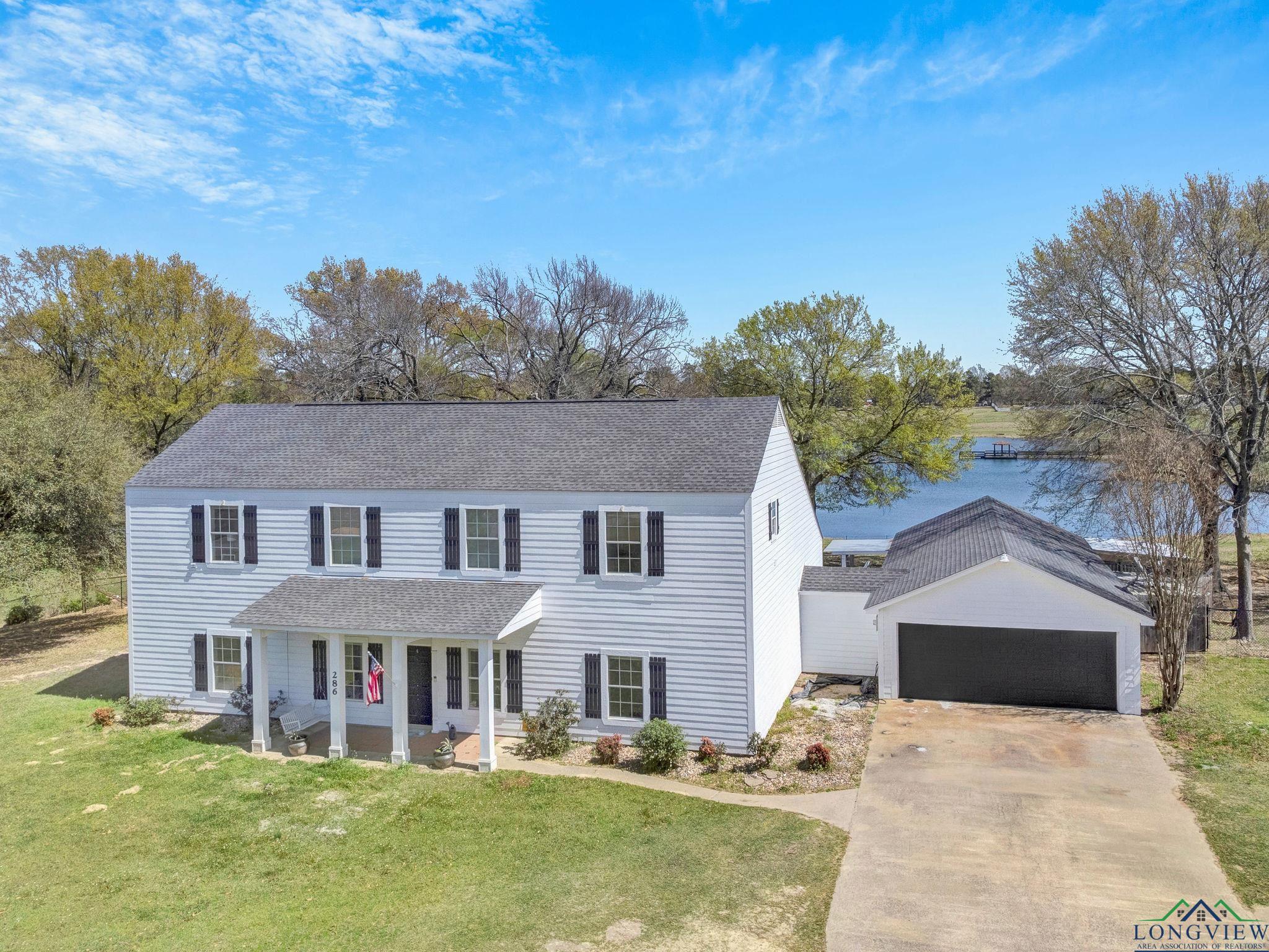Image 0: View of front of house with roof with shingles, a detached garage, driveway, a front yard, and covered porch, Front Of Structure