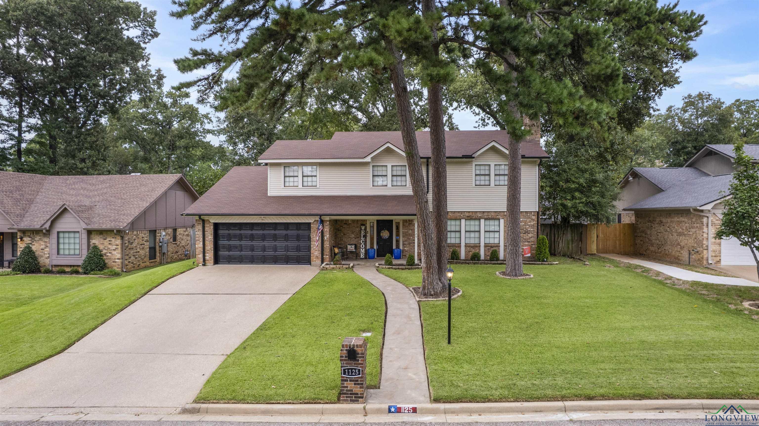 Image 0: Traditional home with concrete driveway, covered porch, a garage, brick siding, and roof with shingles, Front Of Structure