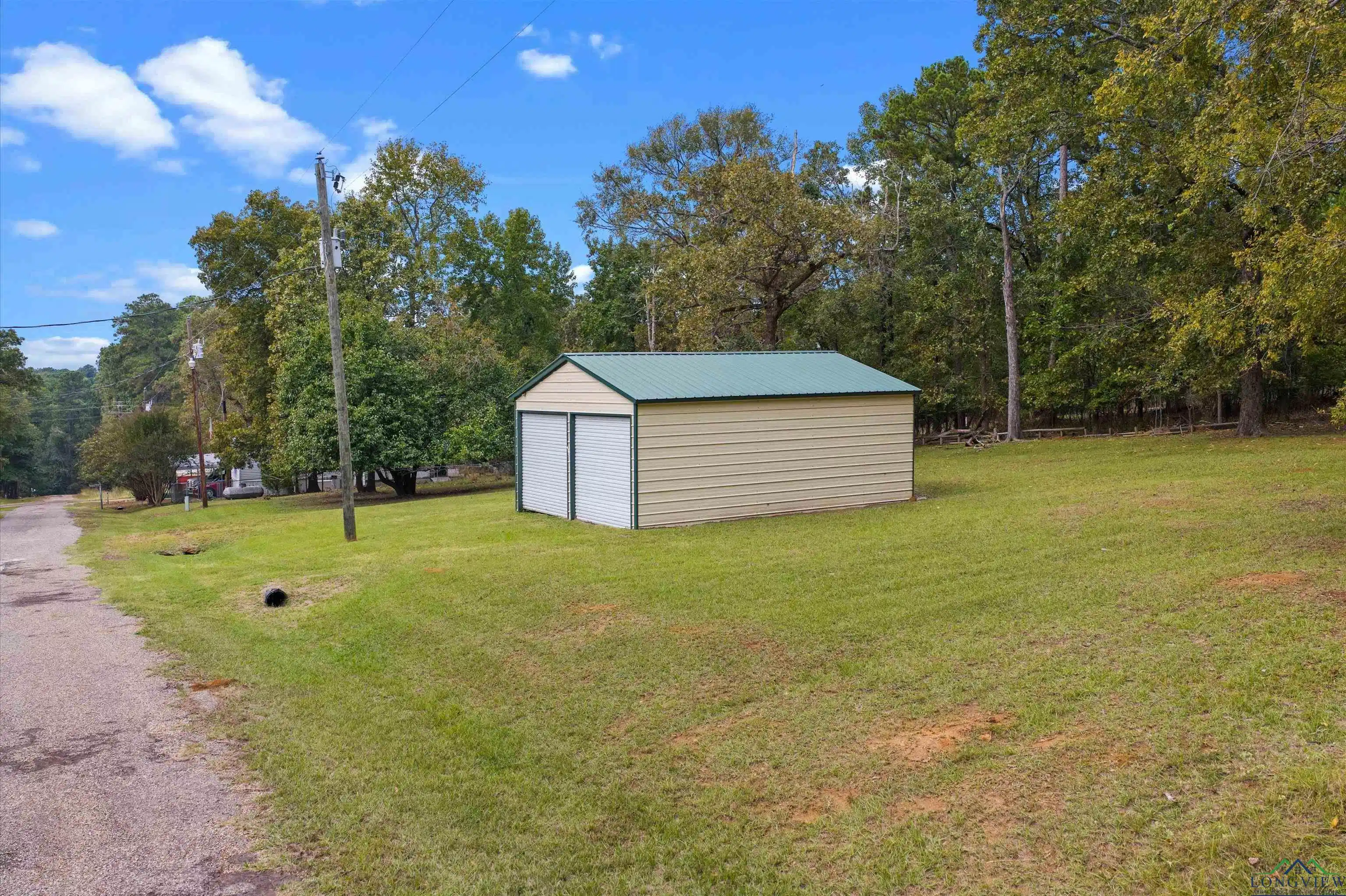 Image 0: View of grassy yard with an outdoor structure and view of scattered trees, Yard