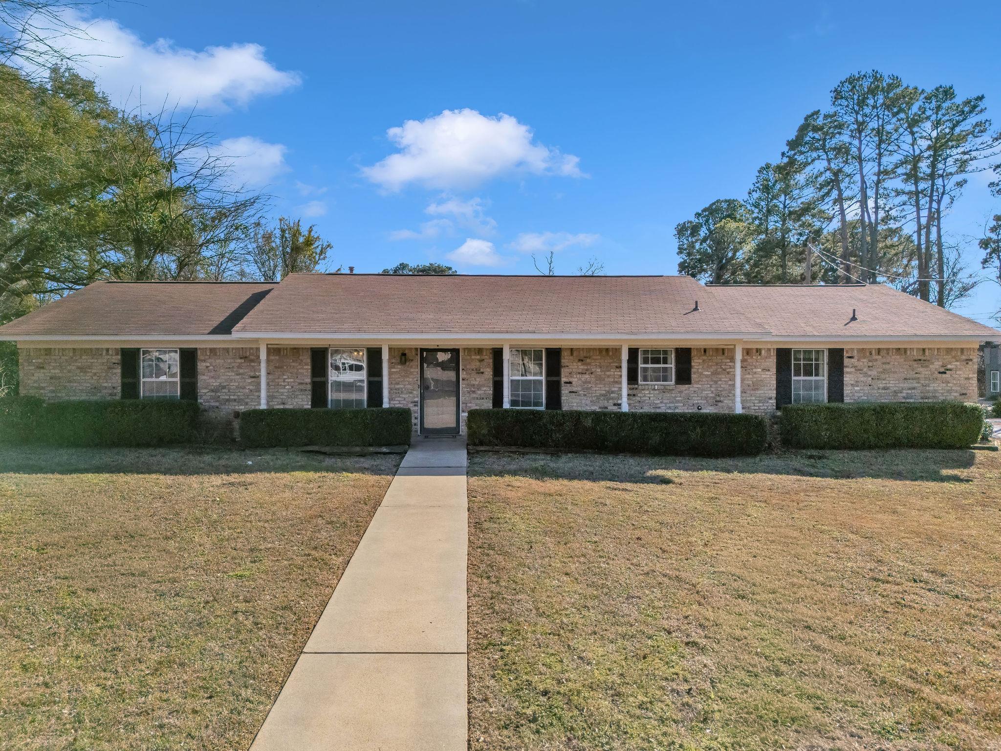 Image 0: Single story home featuring a front lawn, brick siding, a shingled roof, and covered porch, Front Of Structure