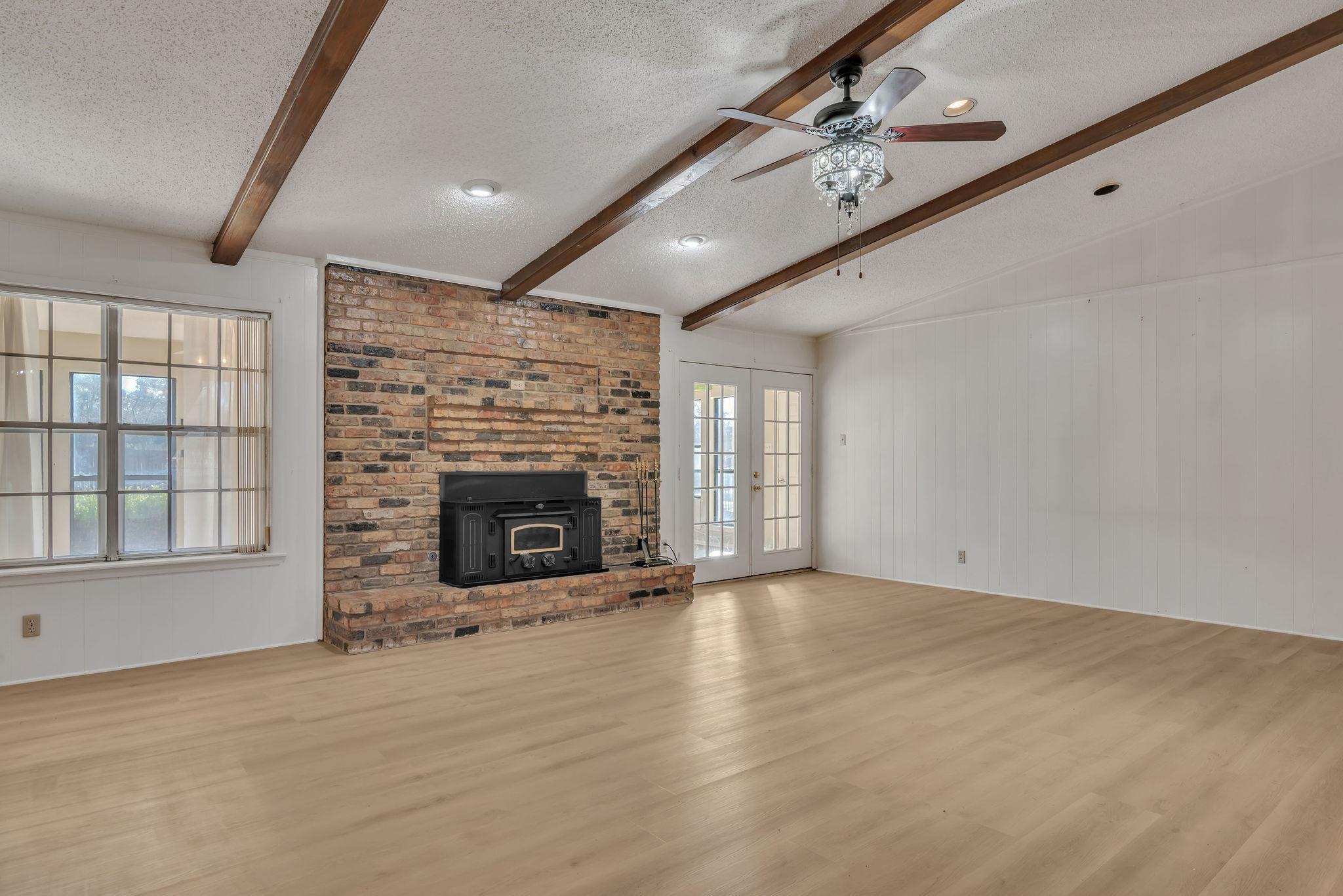 Image 3: Unfurnished living room with french doors, a ceiling fan, wood finished floors, wooden walls, and beamed ceiling, Living Room