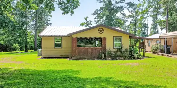 Image 2: Exterior featuring a metal roof, yellow siding, and a covered porch with natural wood accents, Front Of Structure