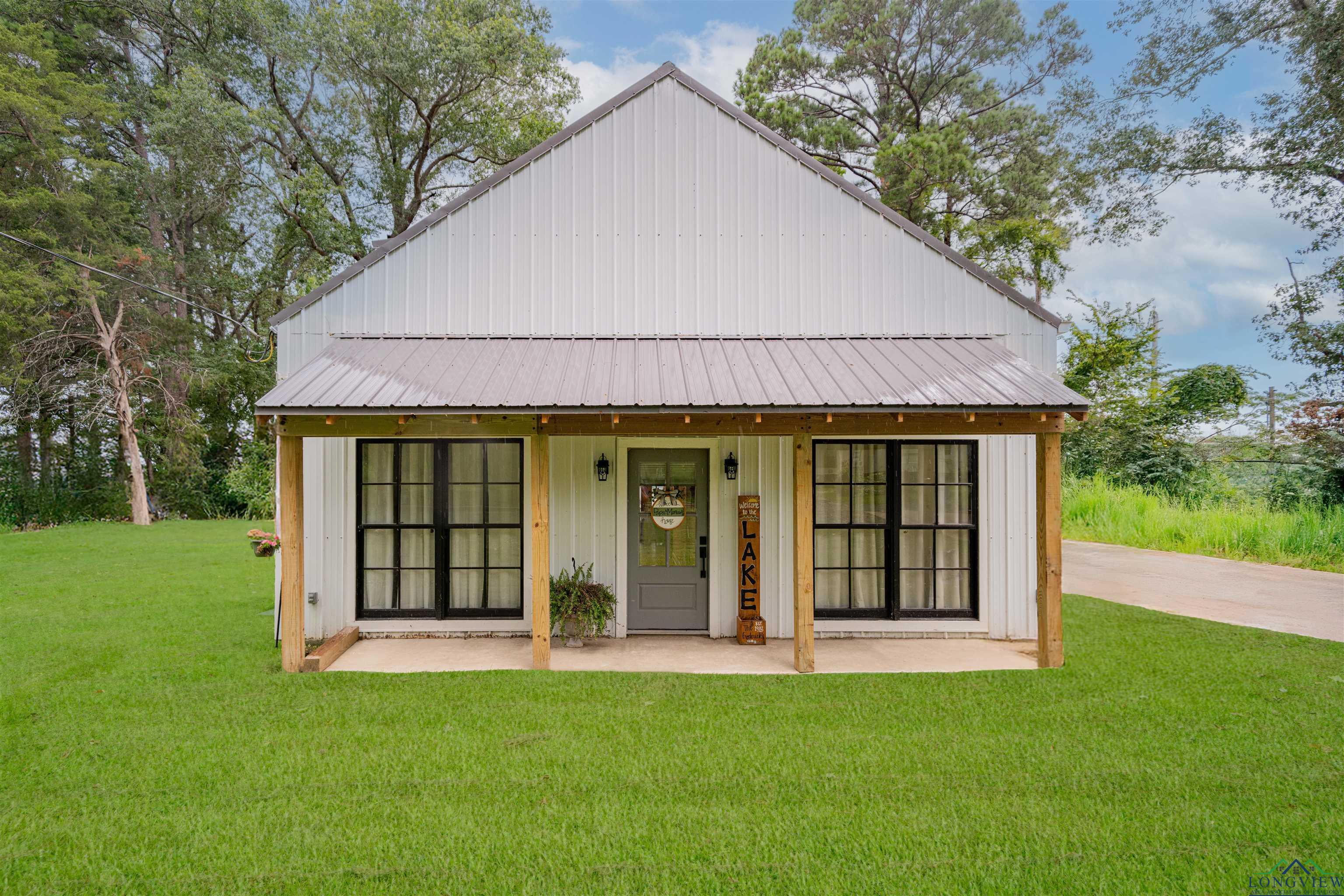 Image 0: View of front of house with a front yard, a metal roof, and board and batten siding, Front Of Structure