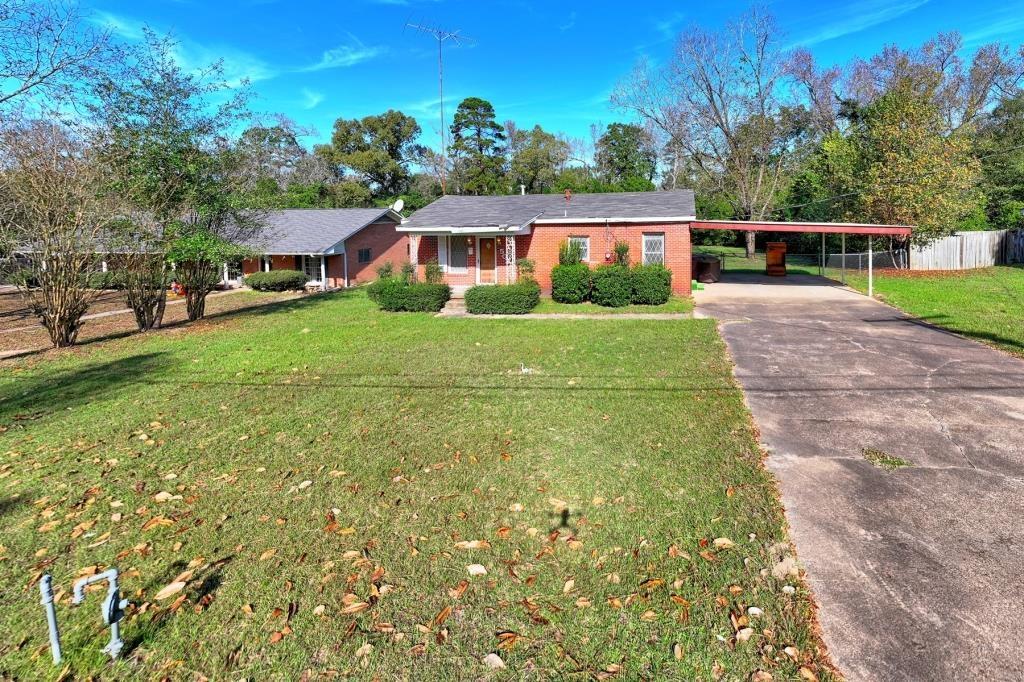 Image 0: Ranch-style home featuring a porch, concrete driveway, a carport, and brick siding, Front Of Structure