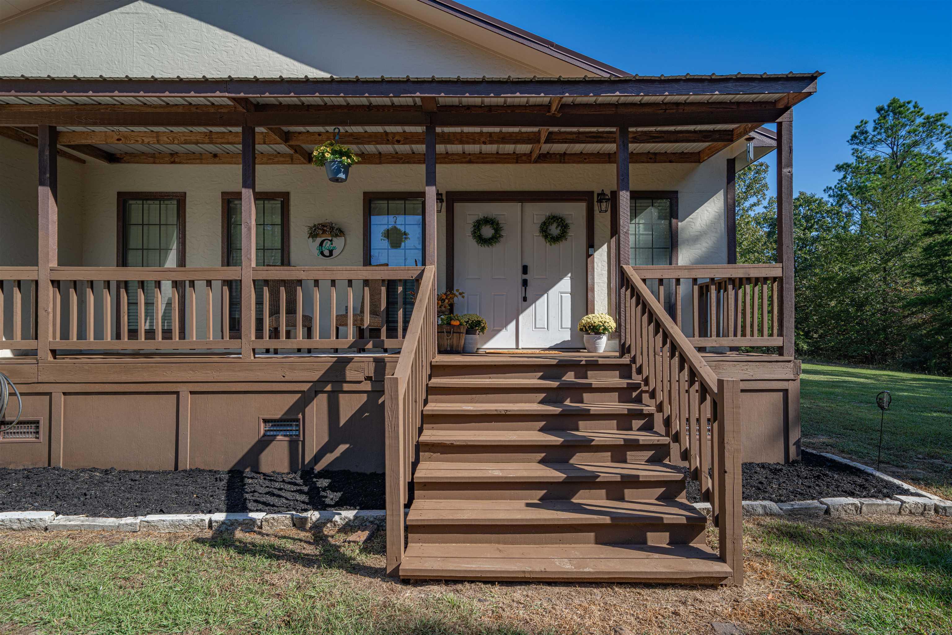 Image 1: Covered front porch featuring a metal roof, wood-finish columns, wood-finish railing, and a multi-step entry, Entry