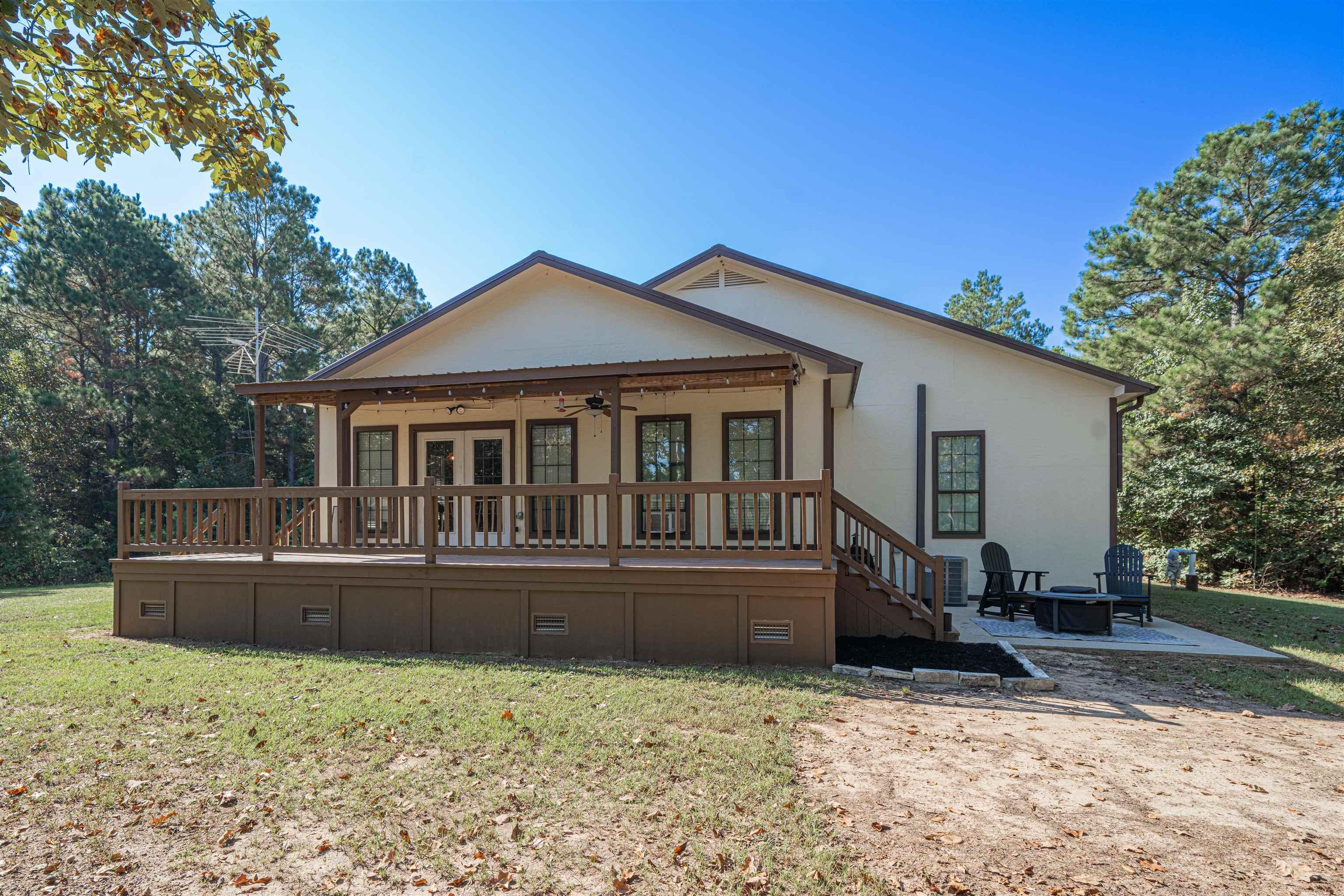 Image 2: Rear exterior featuring a covered porch, wood deck, and outdoor patio with a fire pit, Back Of Structure