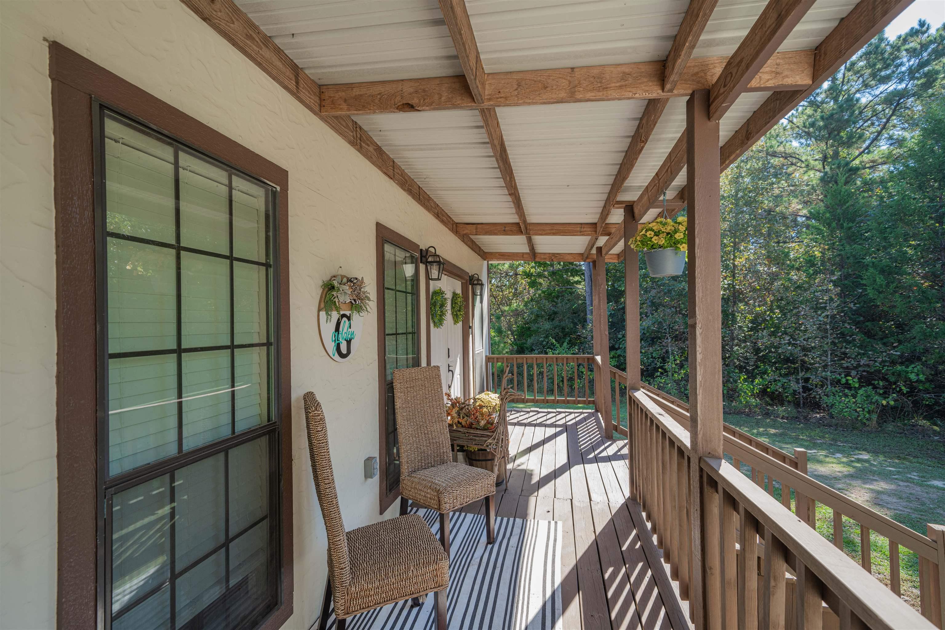 Image 3: Covered porch featuring a wood-finish deck, exposed wood beams, and a corrugated metal roof, Deck