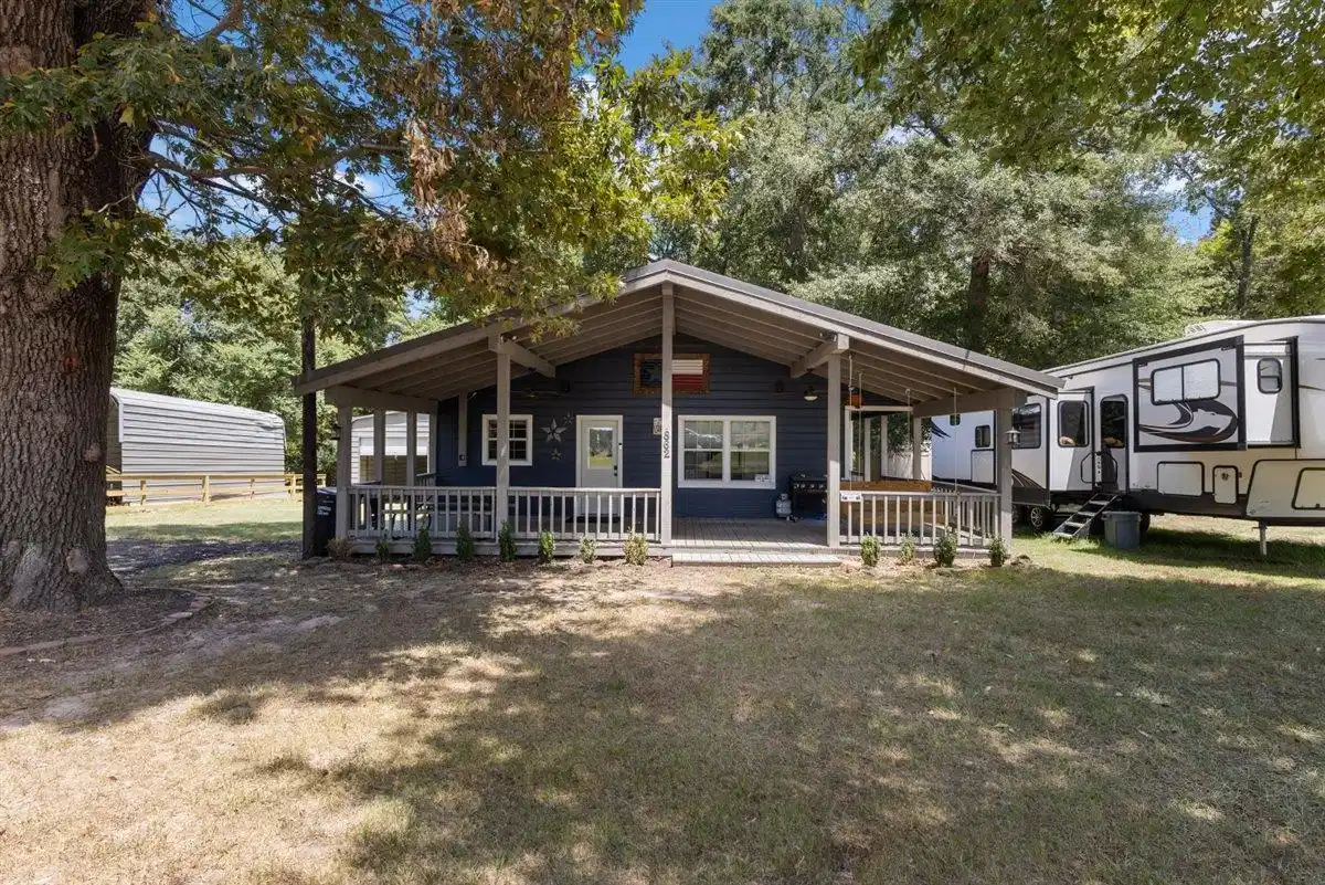 Image 0: Exterior featuring a deep covered porch, white railing, blue siding, and white trim windows, Front Of Structure
