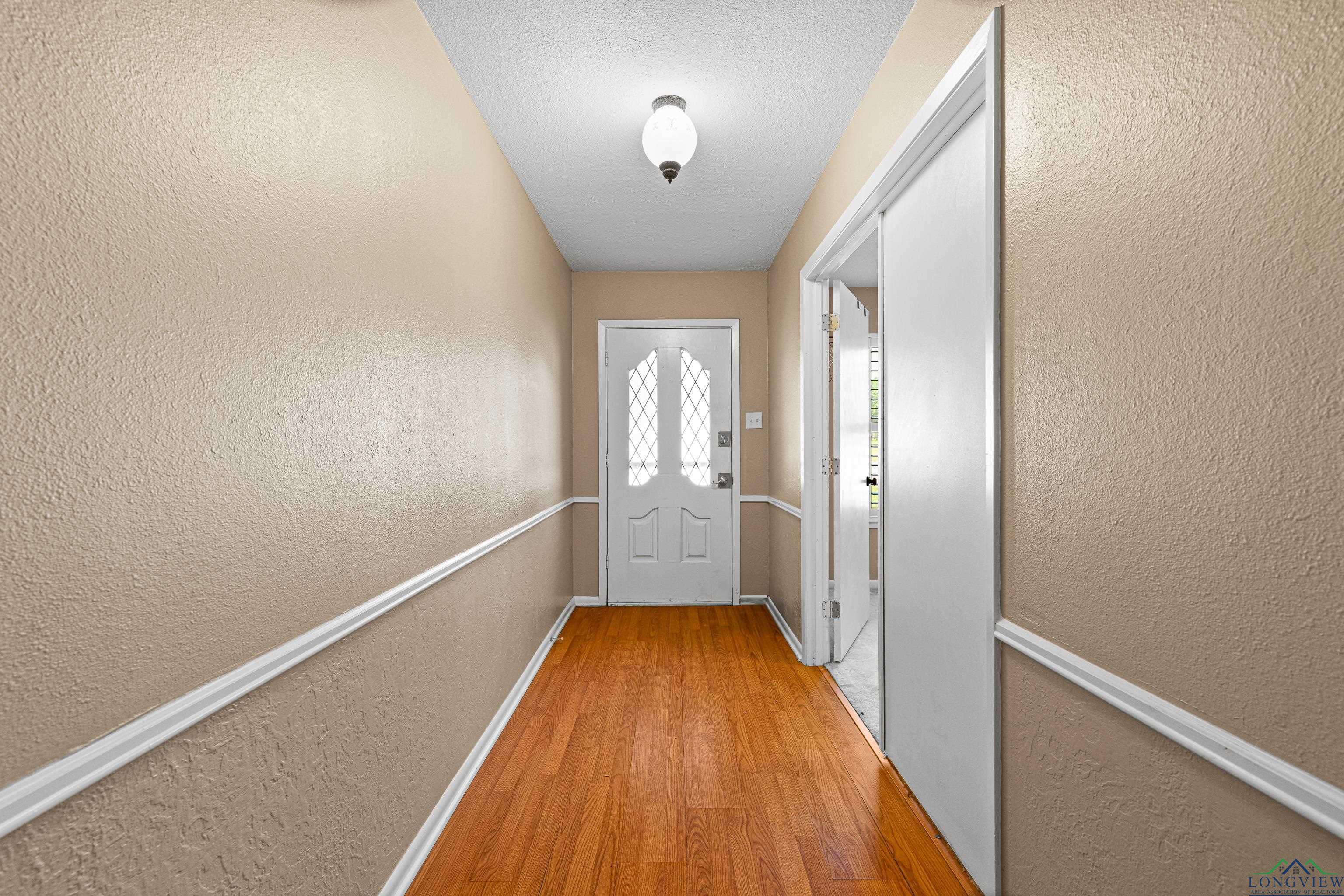 Image 3: Doorway to outside featuring a textured wall, baseboards, and wood finished floors, Entry