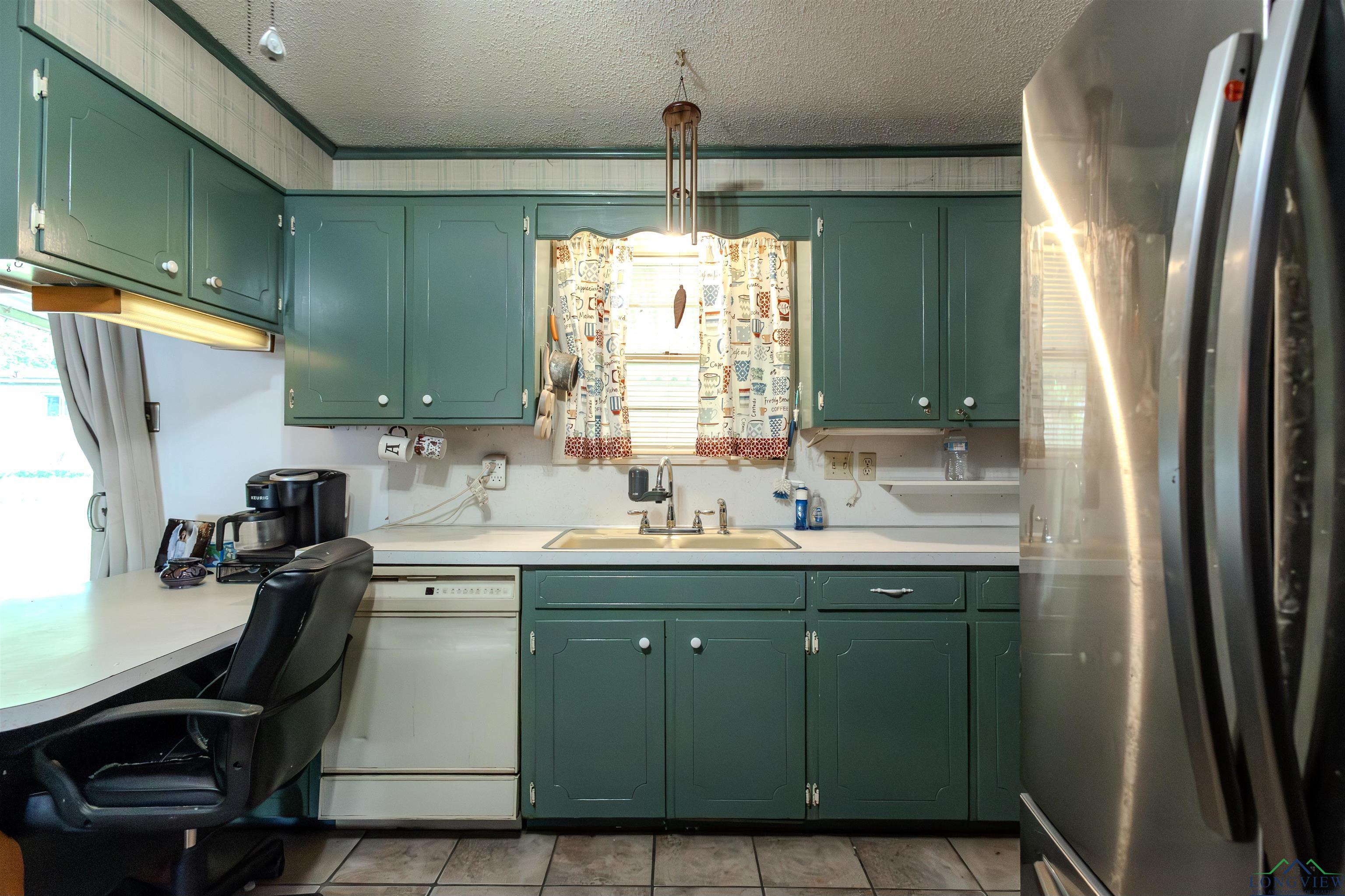 Image 2: Kitchen with freestanding refrigerator, green cabinets, light countertops, a textured ceiling, and dishwasher, Kitchen