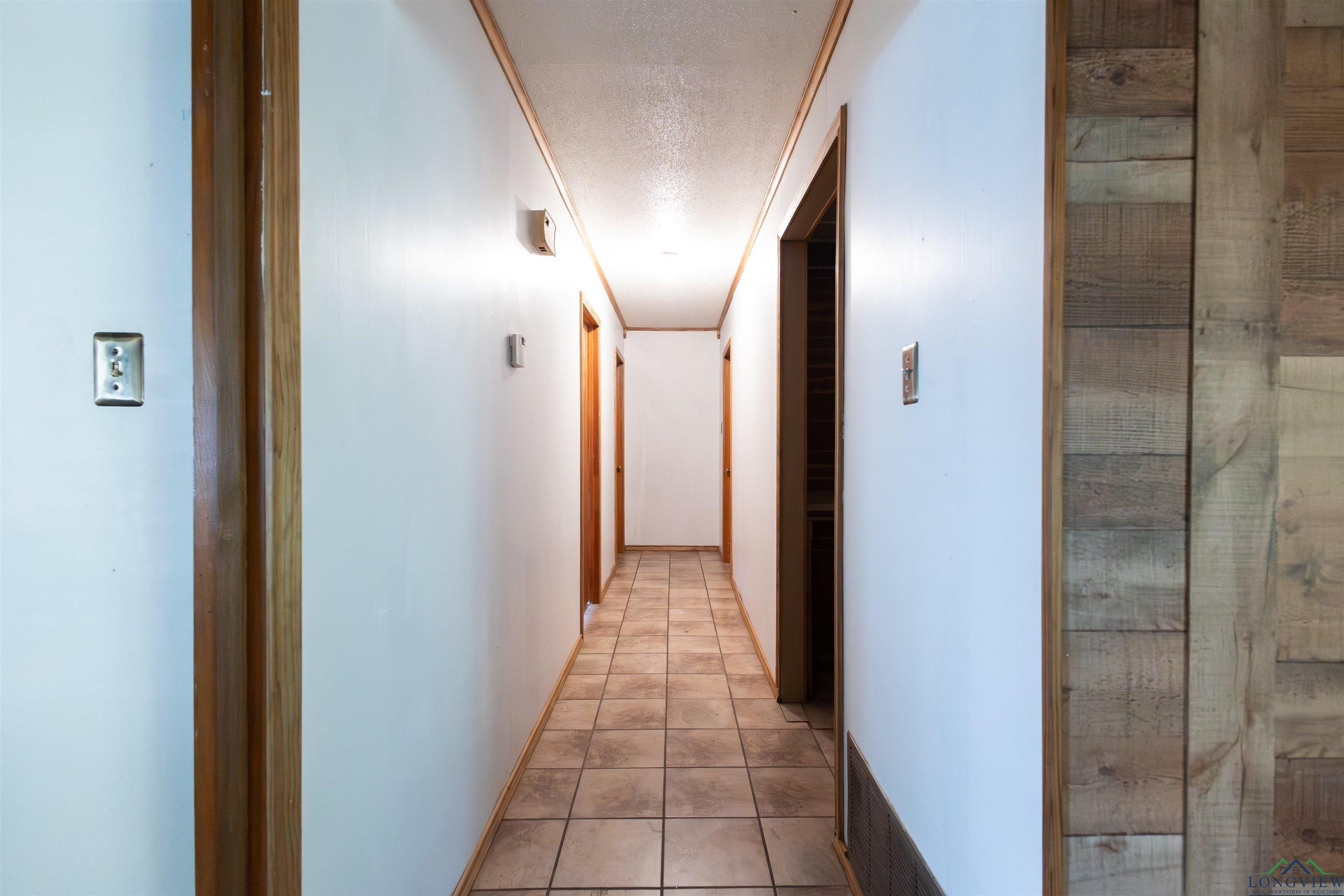 Image 3: Corridor with a textured ceiling and light tile patterned floors, Hallway