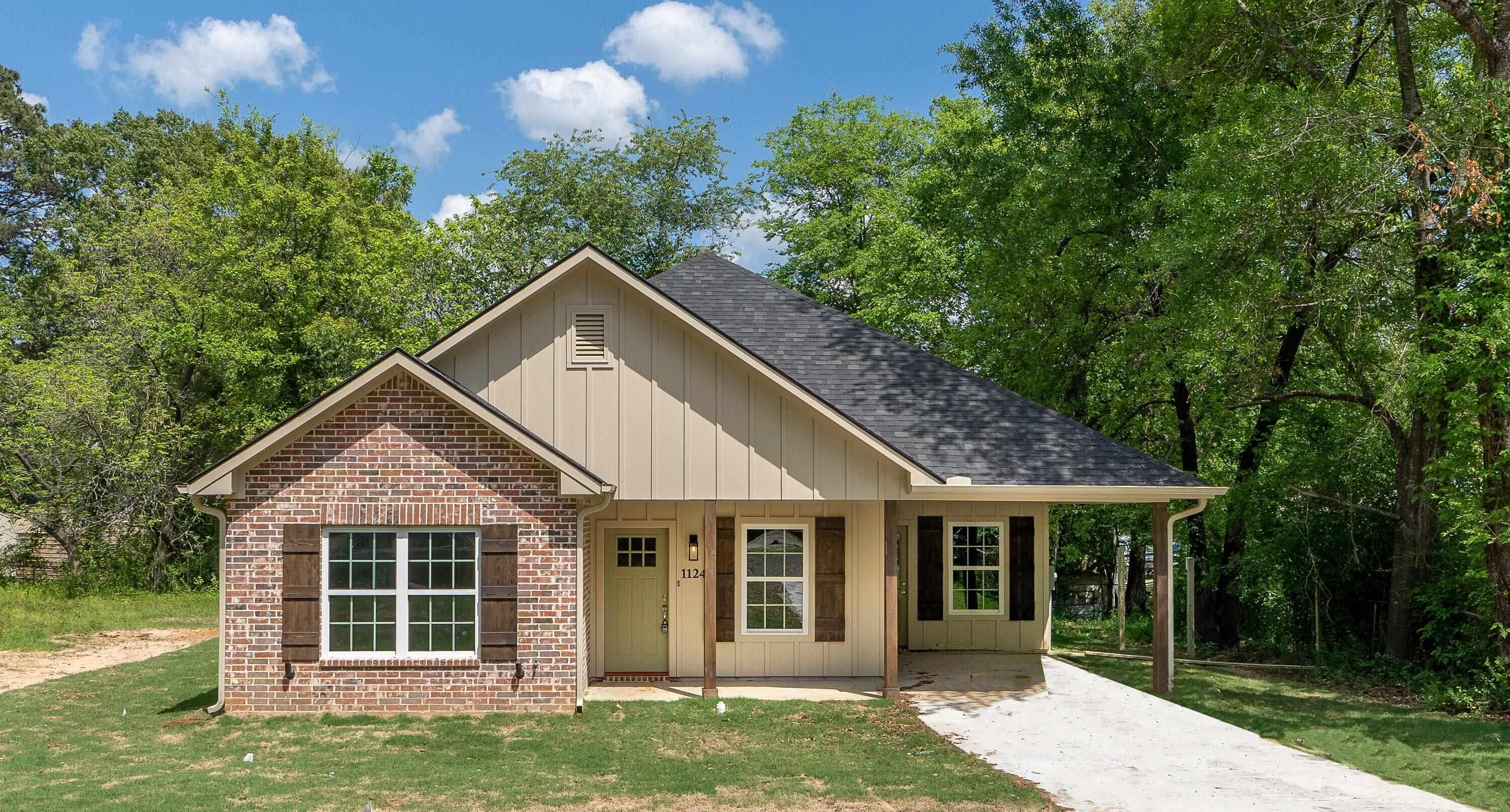 Image 1: View of front of property featuring board and batten siding, a front lawn, covered porch, a shingled roof, and brick siding, Front Of Structure