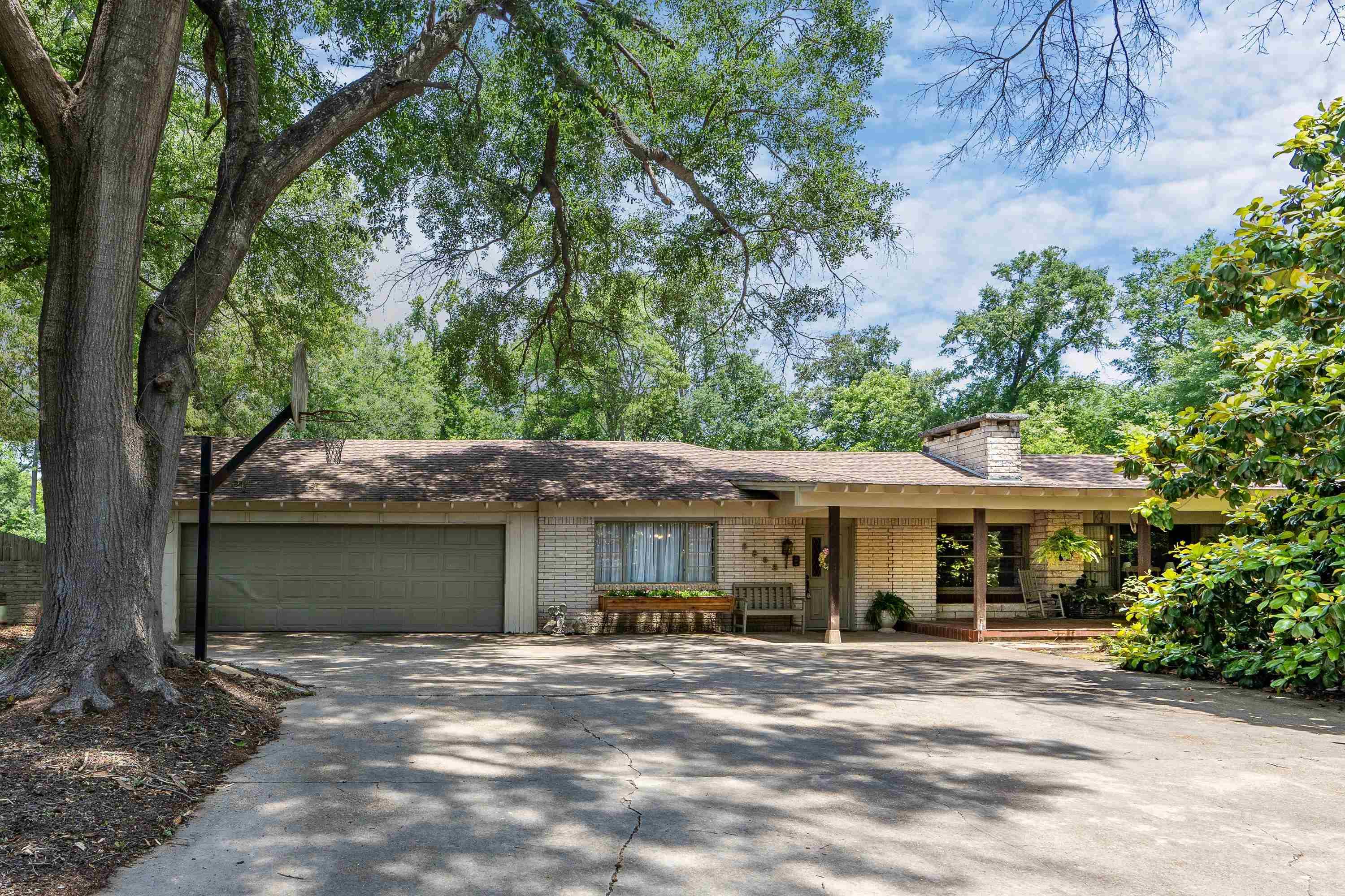 Image 0: Ranch-style residence featuring a prominent mature tree, an attached two-car garage, and a covered front porch with wood columns, Front Of Structure