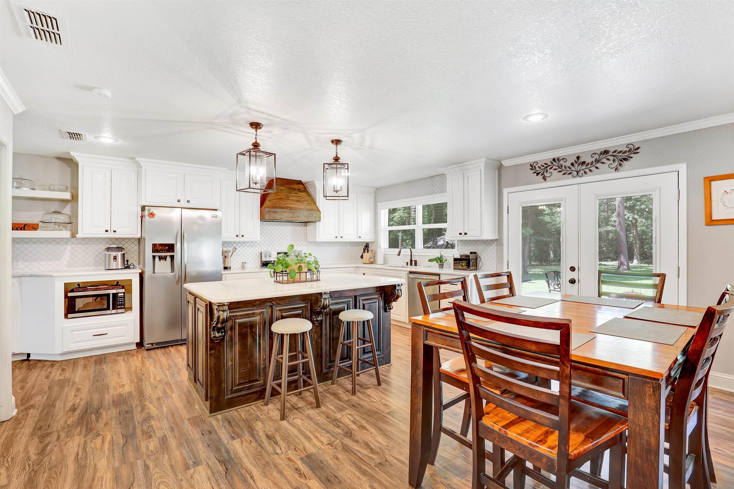Image 2: Kitchen featuring wood-finish flooring, white cabinetry, and a dark-stained island with a light-colored countertop, Dining Area