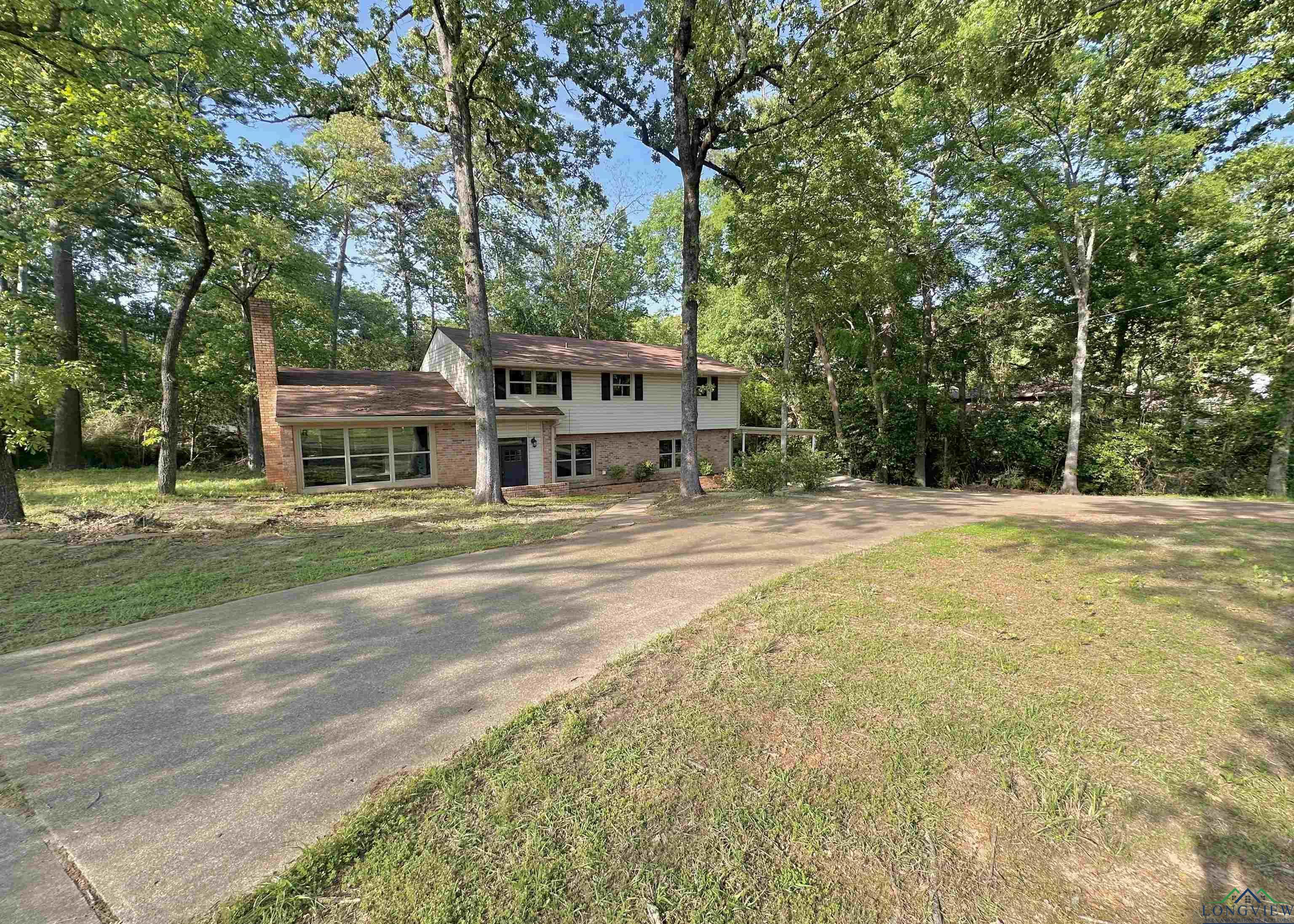 Image 1: View of front of house with brick siding, a front lawn, and concrete driveway, Front Of Structure