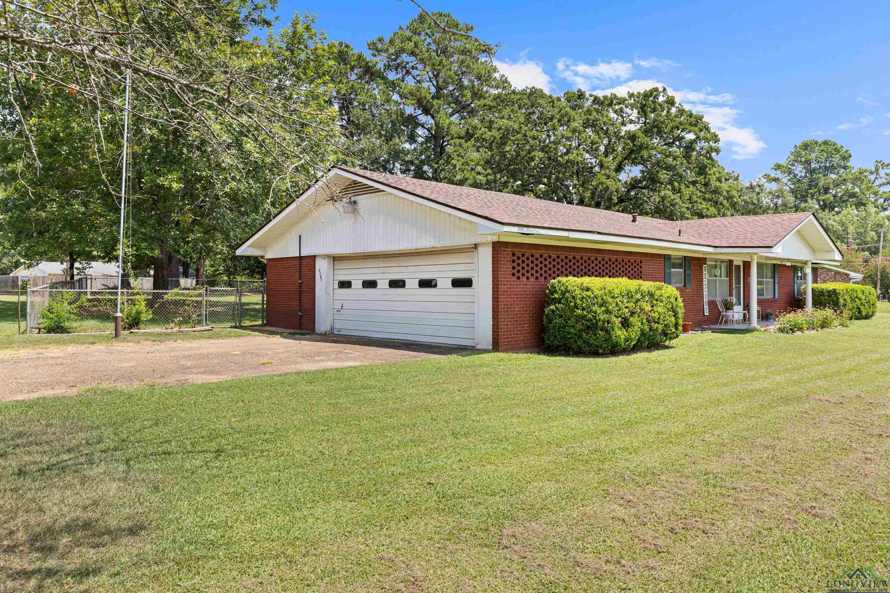 Image 2: Ranch-style house featuring brick siding, driveway, a garage, roof with shingles, and covered porch, Front Of Structure