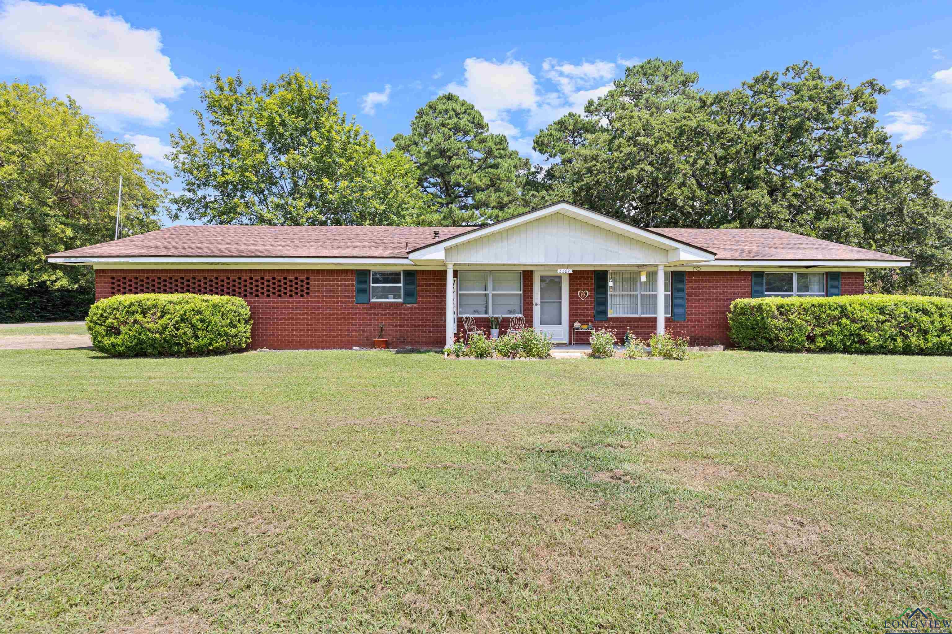 Image 3: Ranch-style house with a porch, brick siding, a front yard, and roof with shingles, Front Of Structure