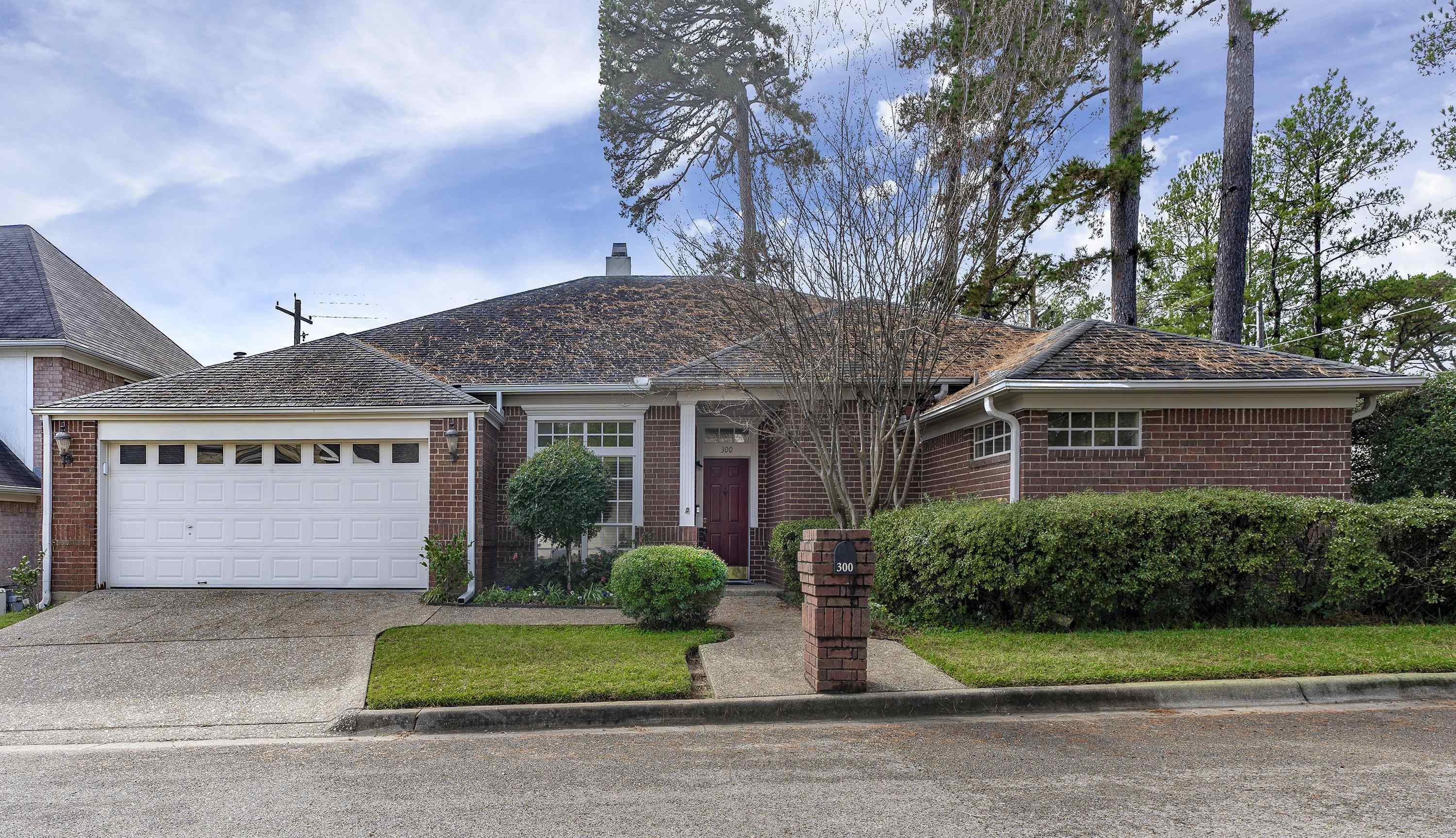 Image 0: View of front facade featuring brick siding, concrete driveway, a garage, and a chimney, Front Of Structure