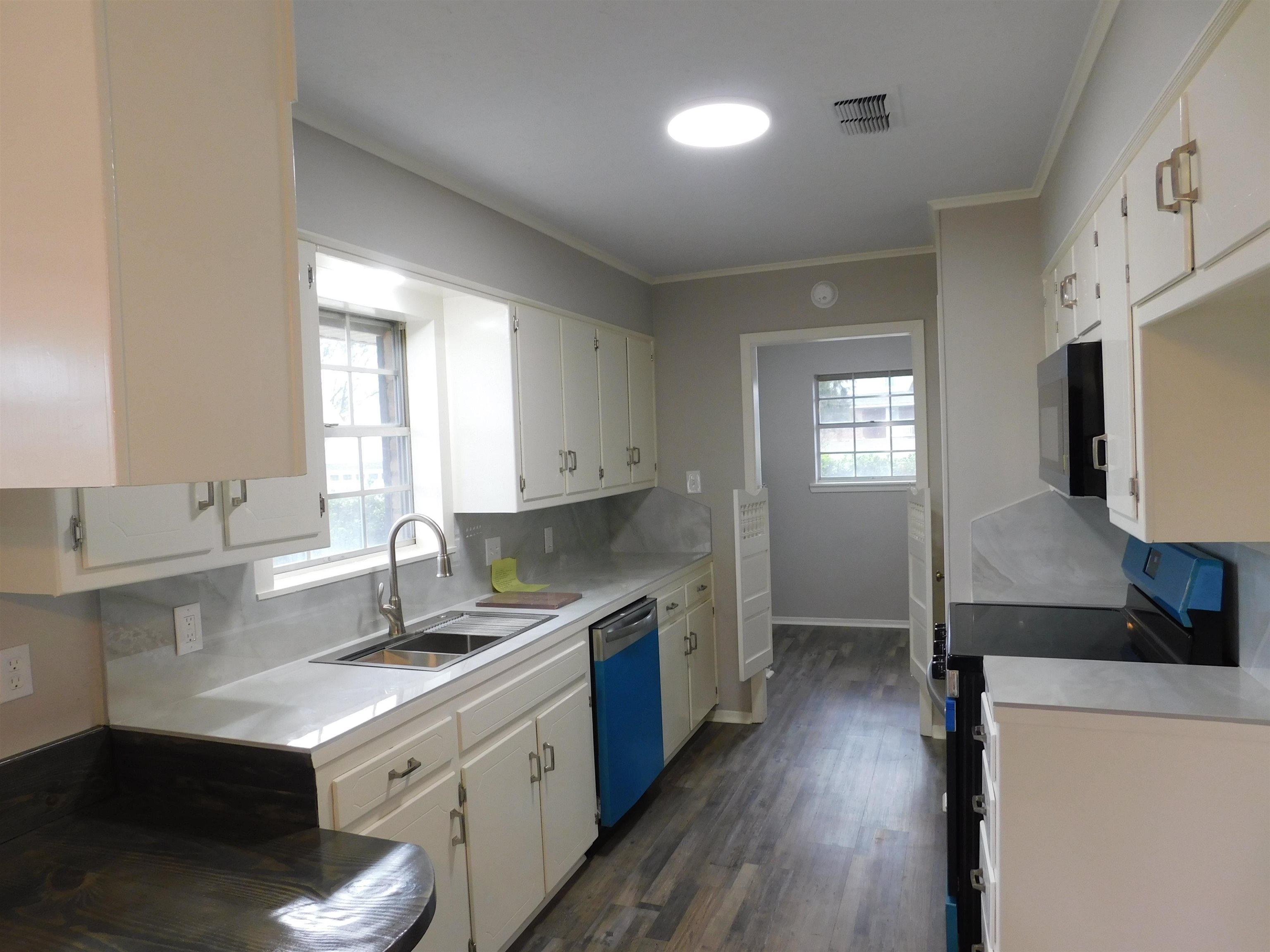 Image 1: Kitchen with electric range, light countertops, backsplash, dark wood finished floors, and white cabinetry, Kitchen