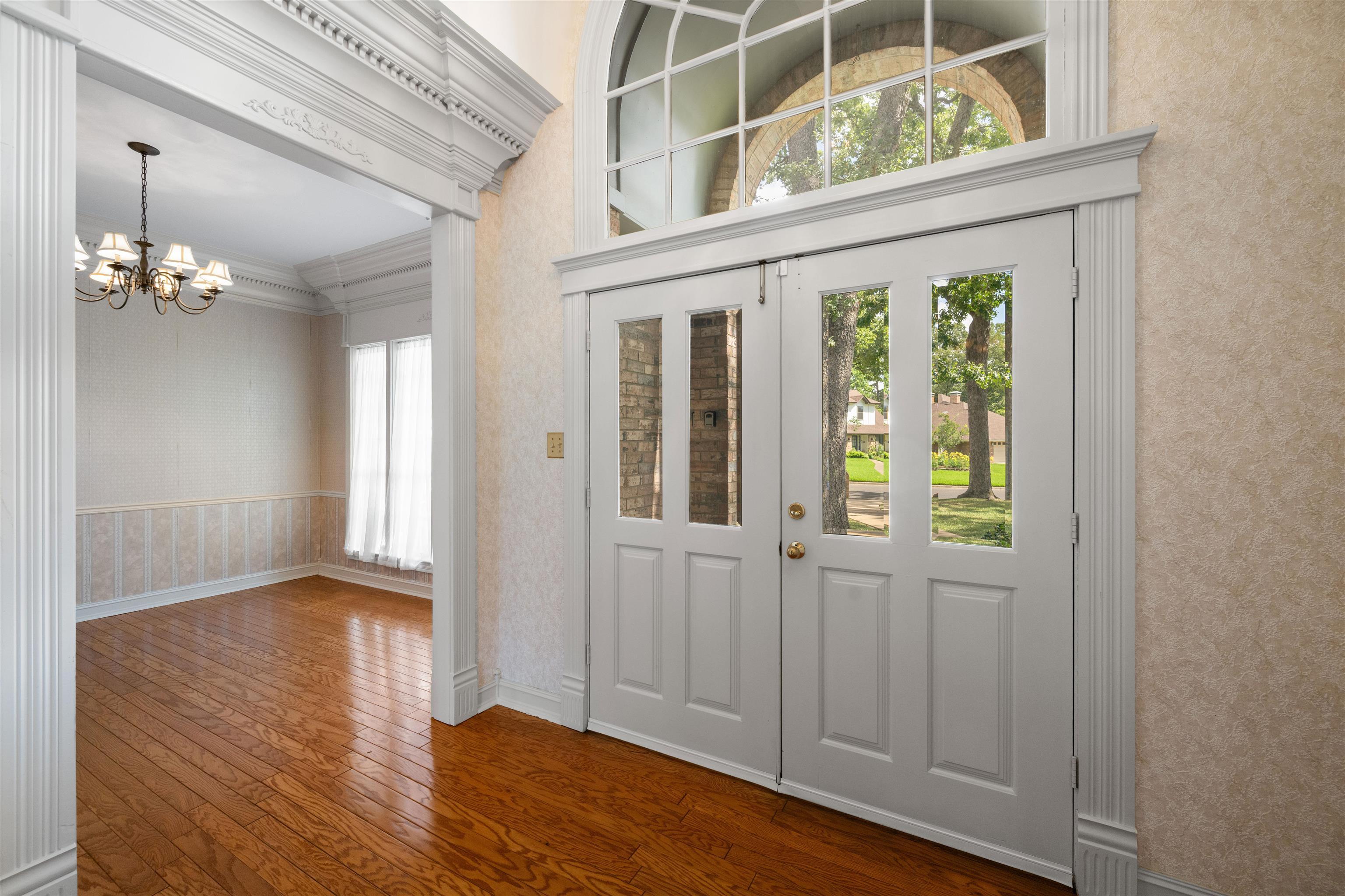 Image 1: Entryway featuring double doors with glass panels, an arched transom window, and access directly into dining room and first living room., Entrance Foyer