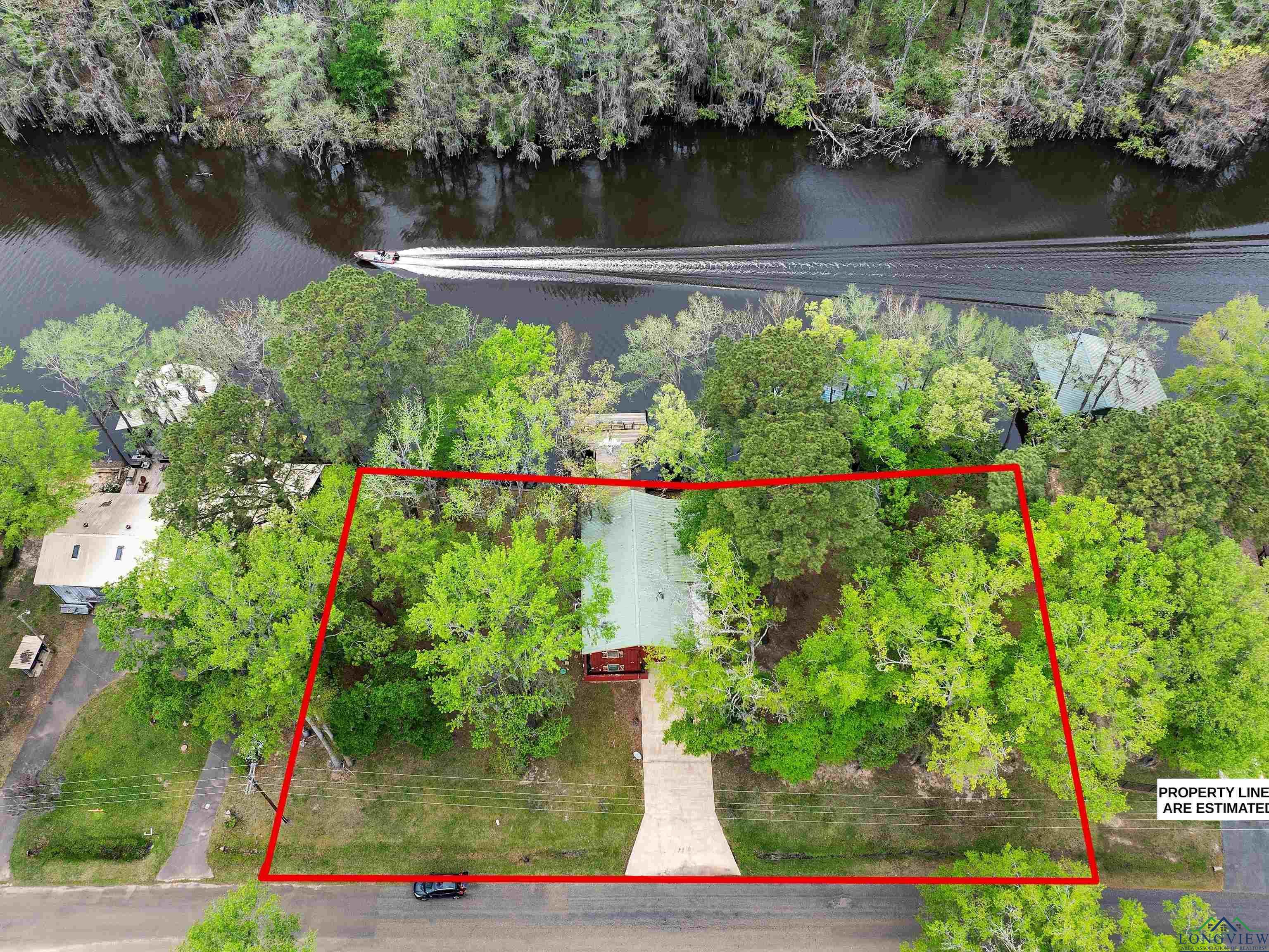 Image 3: Aerial view of property and surrounding area with property boundaries highlighted and a large body of water, Aerial View