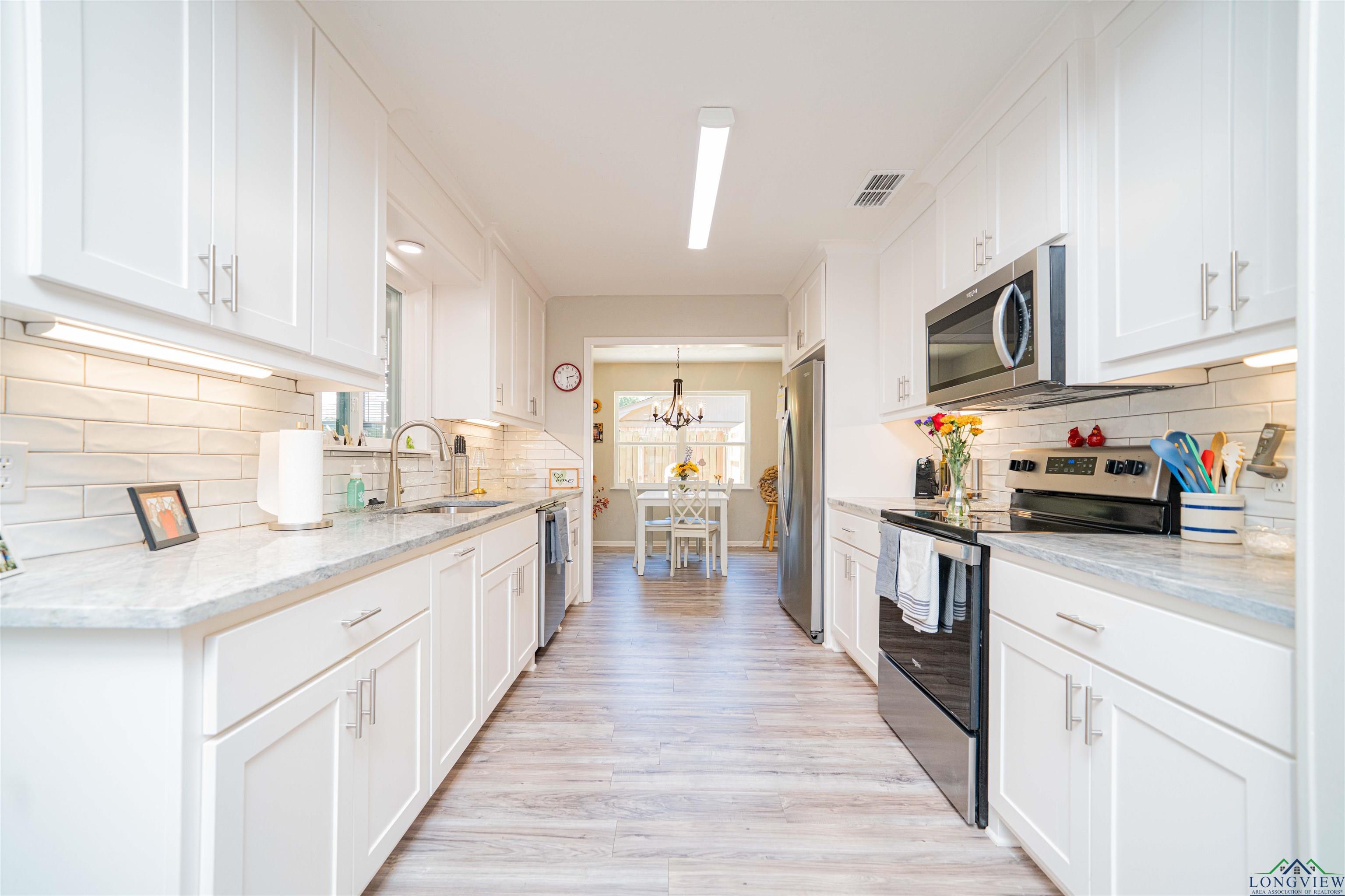 Image 3: Kitchen with stainless steel appliances, healthy amount of natural light, decorative backsplash, and white cabinetry, Kitchen