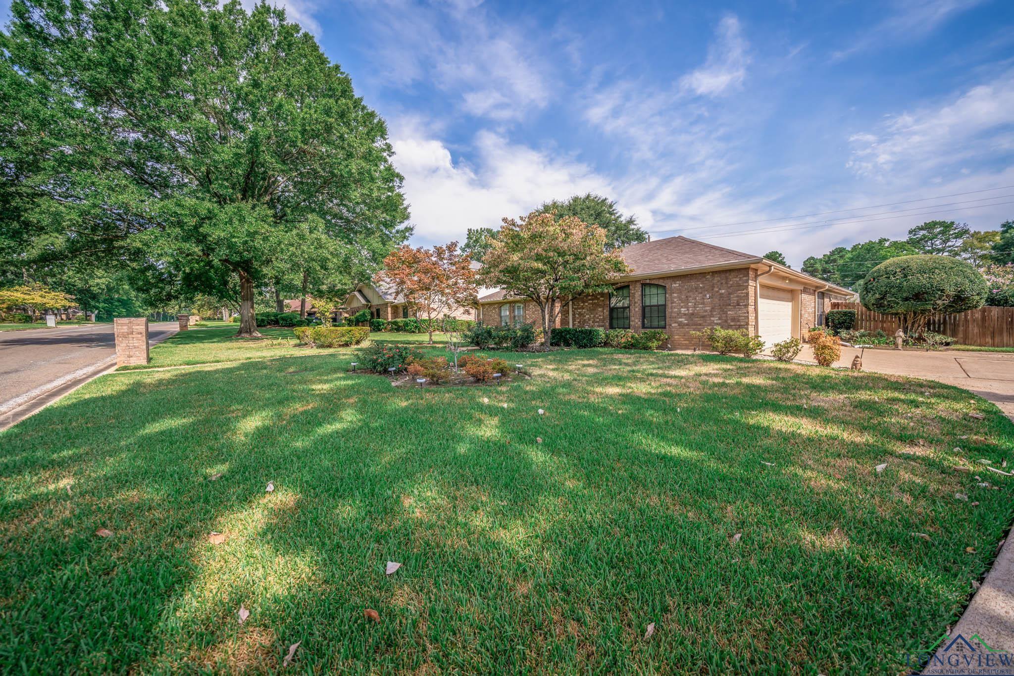 Image 1: View of front of house featuring an attached garage, brick siding, and concrete driveway, Front Of Structure