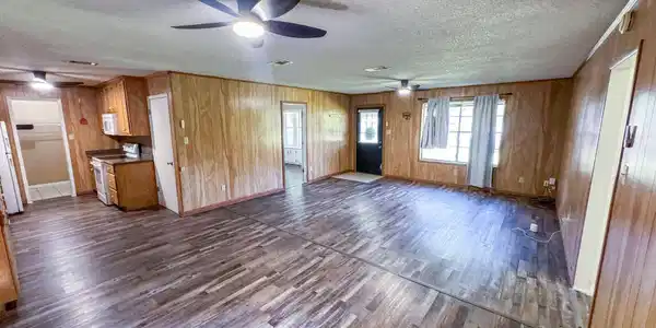 Image 3: Unfurnished living room featuring dark wood finished floors, wooden walls, a textured ceiling, and ceiling fan, Living Room