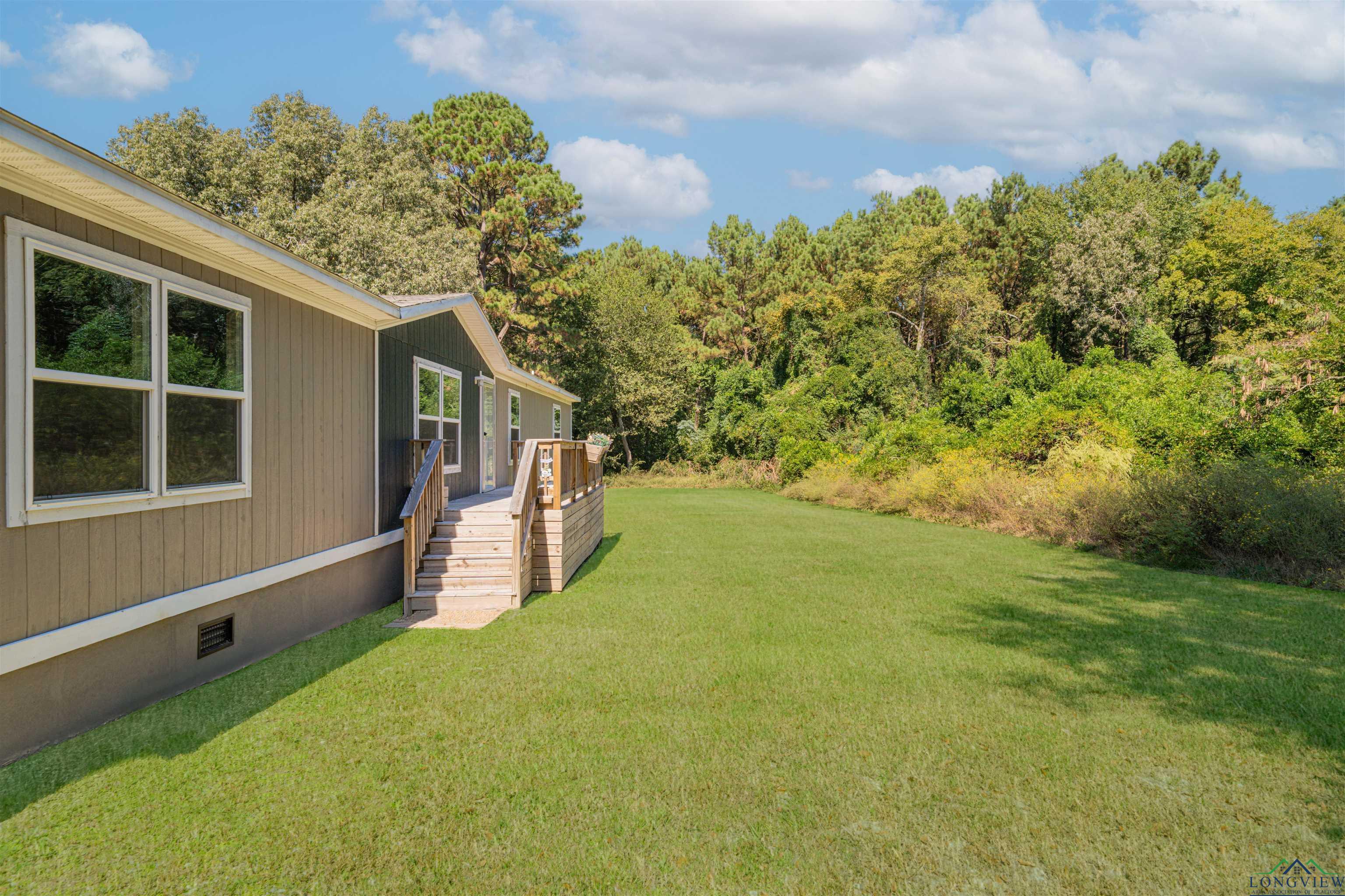 Image 3: View of grassy yard featuring a deck, Yard