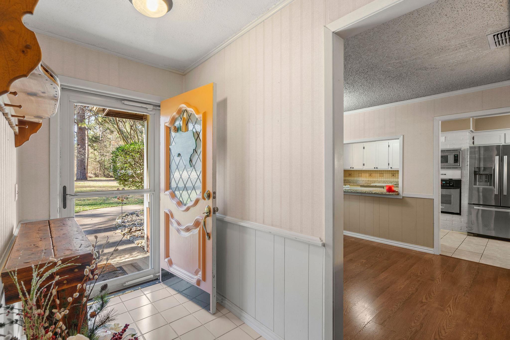 Image 2: Foyer entrance with ornamental molding, a textured ceiling, wainscoting, light wood-style floors, and wooden walls, Entrance Foyer