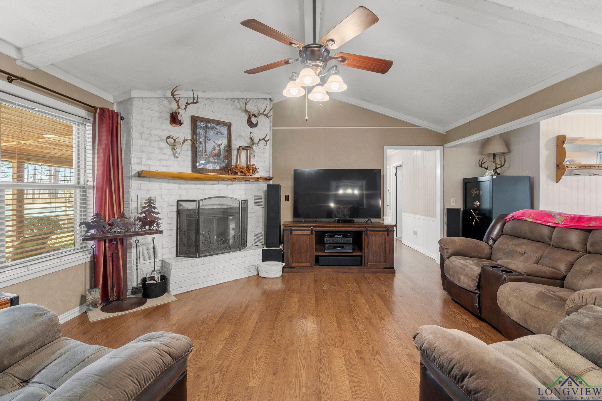 Image 3: Living area with wood finished floors, a fireplace, and a ceiling fan, Living Room