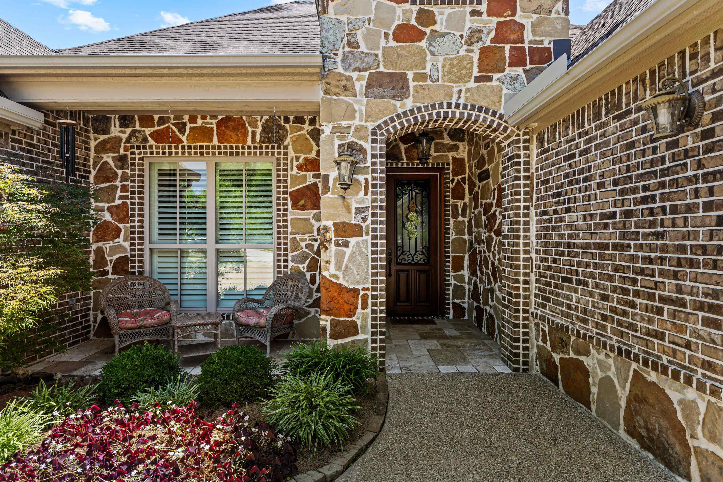 Image 1: Stone and brick facade featuring an arched entryway with a solid wood door, Entry