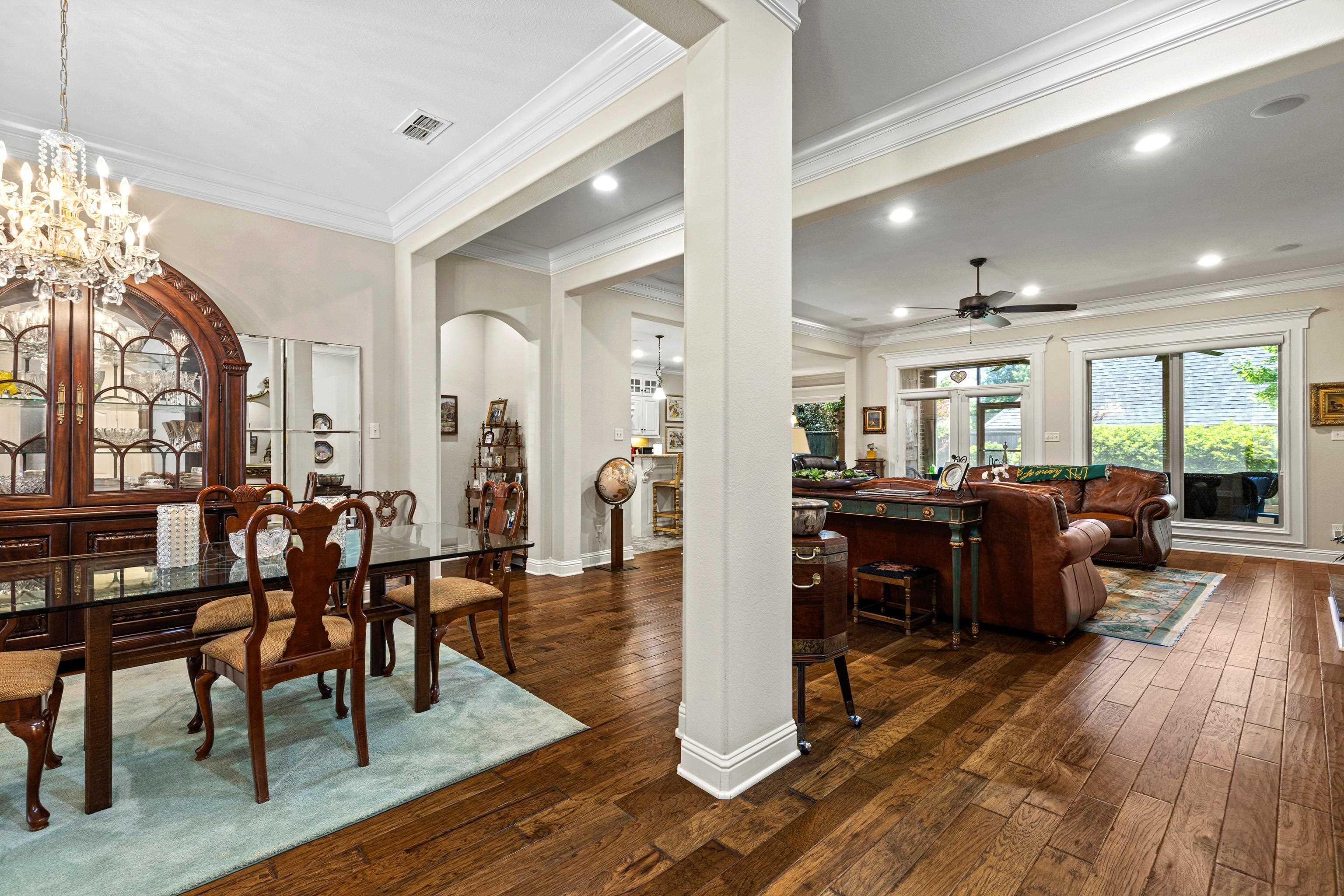 Image 3: Open-concept living area featuring rich wood-finish flooring, recessed lighting, crown molding, and large windows, Dining Area
