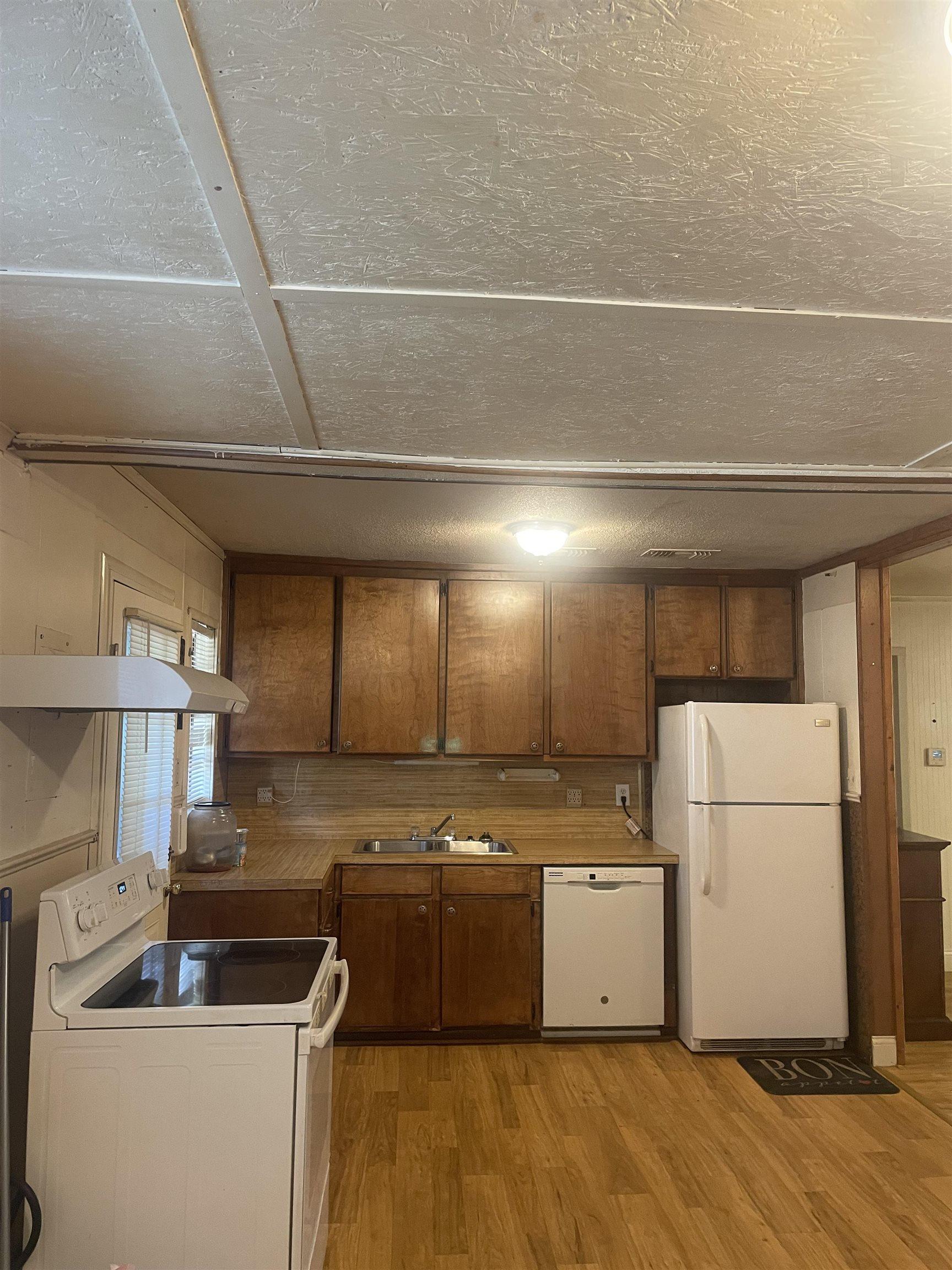 Image 1: Kitchen featuring wood-finish flooring, wood cabinetry, laminate countertops, and white appliances including a range, dishwasher, and refrigerator, Kitchen