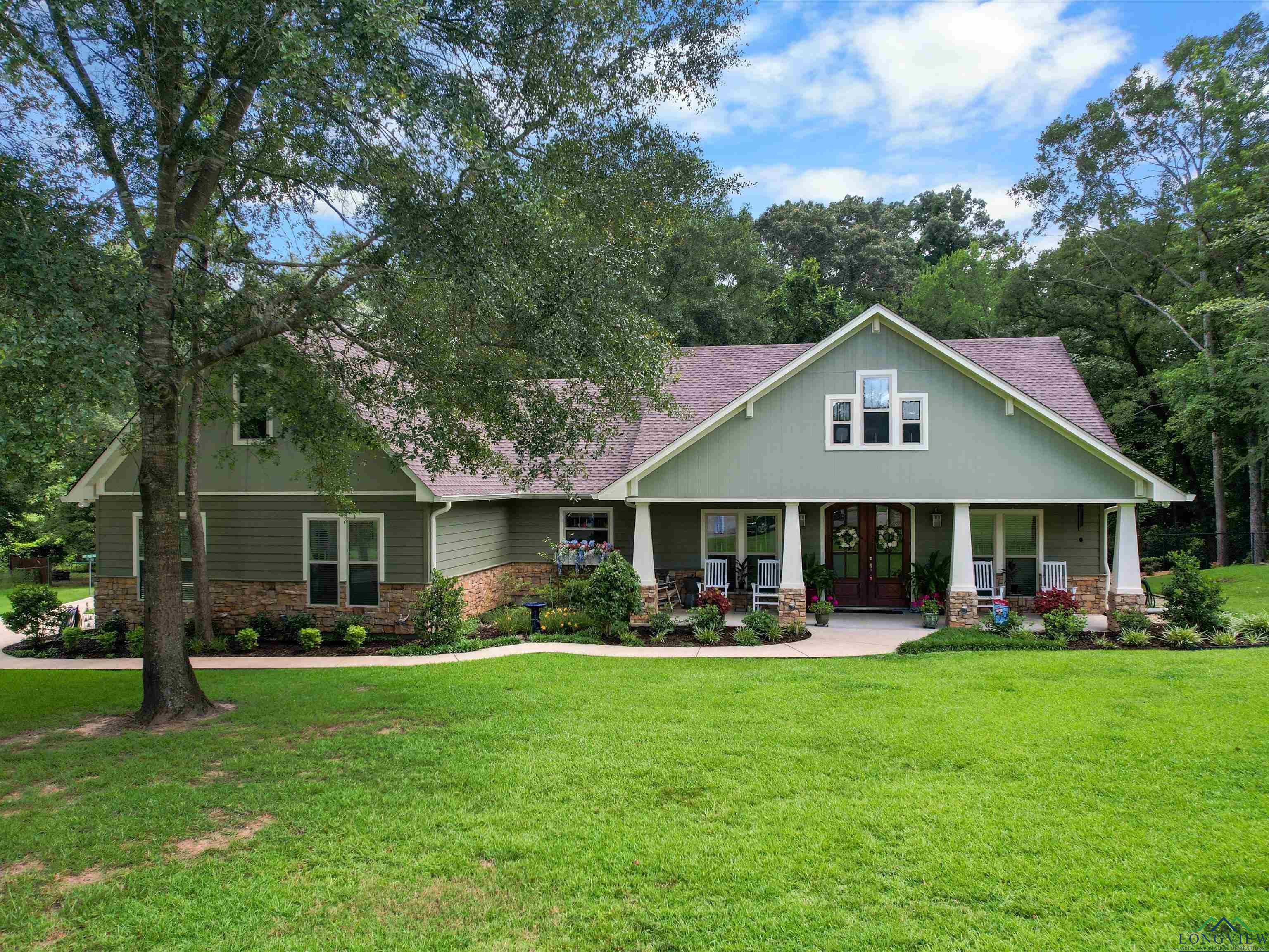 Image 0: Craftsman-style home featuring covered porch, a front lawn, stone siding, and french doors, Front Of Structure
