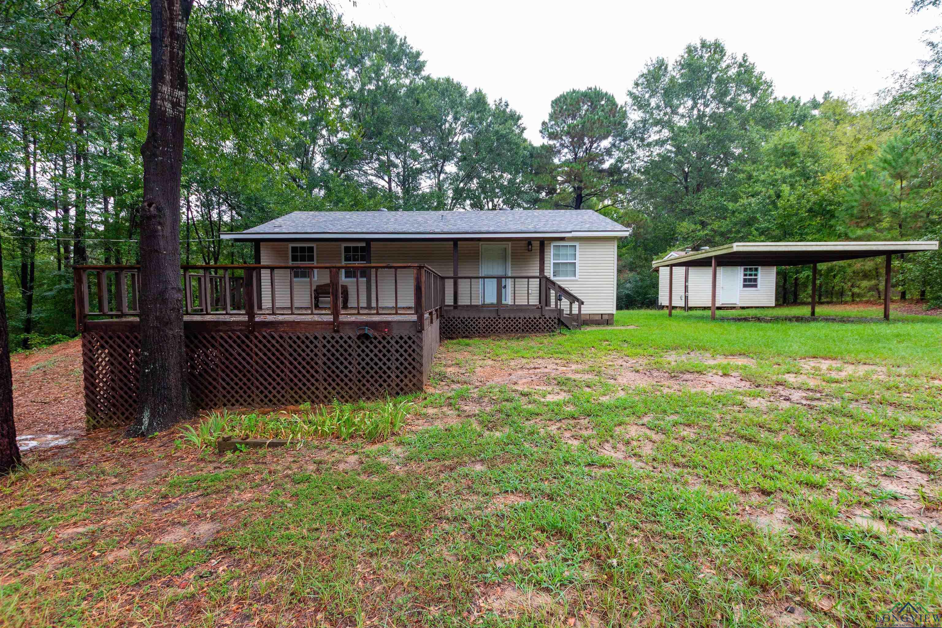 Image 0: Rear view of property featuring a detached carport, an outdoor structure, view of scattered trees, a yard, and crawl space, Back Of Structure